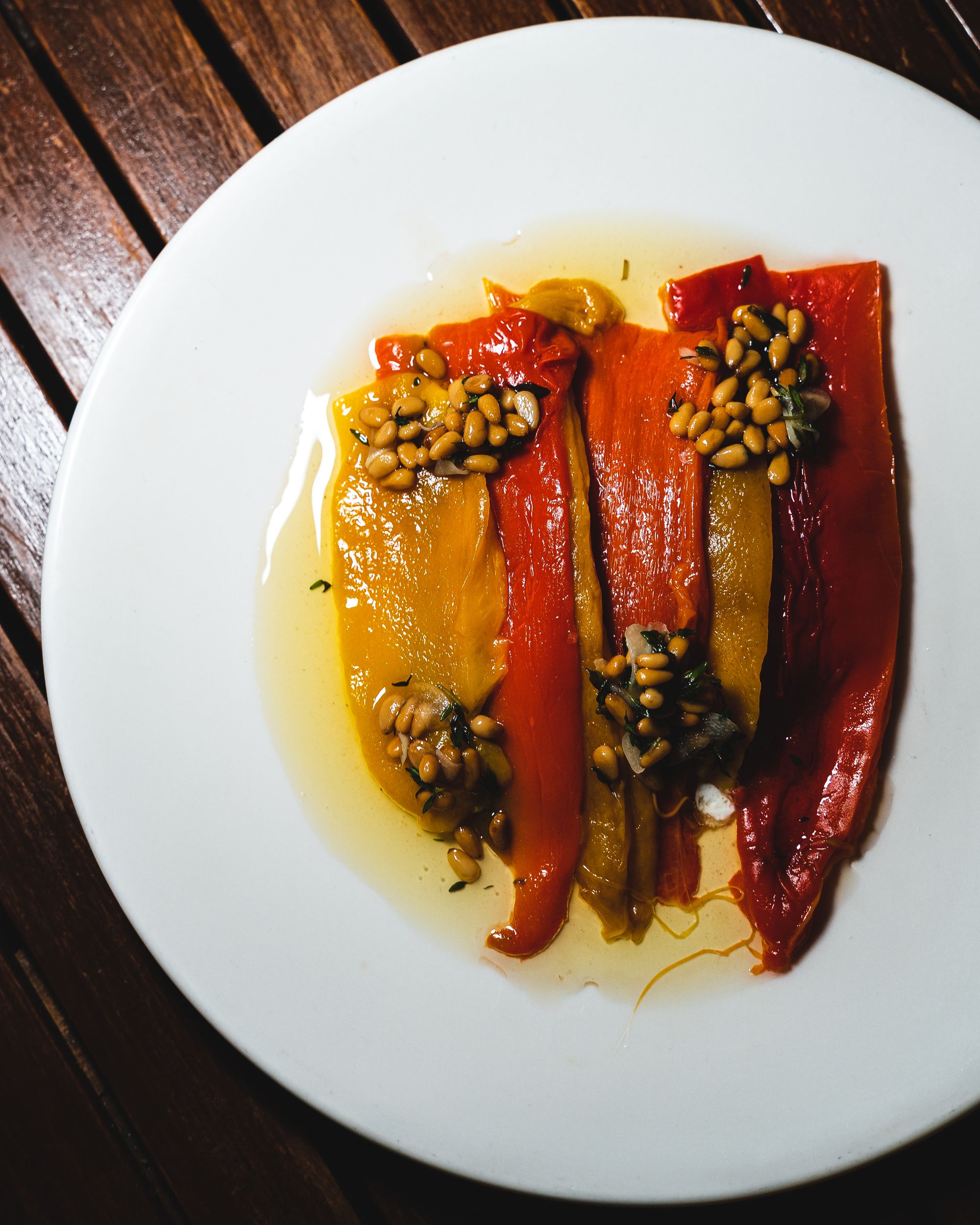 Slices of bell peppers placed on a plate with pine nuts as garnish