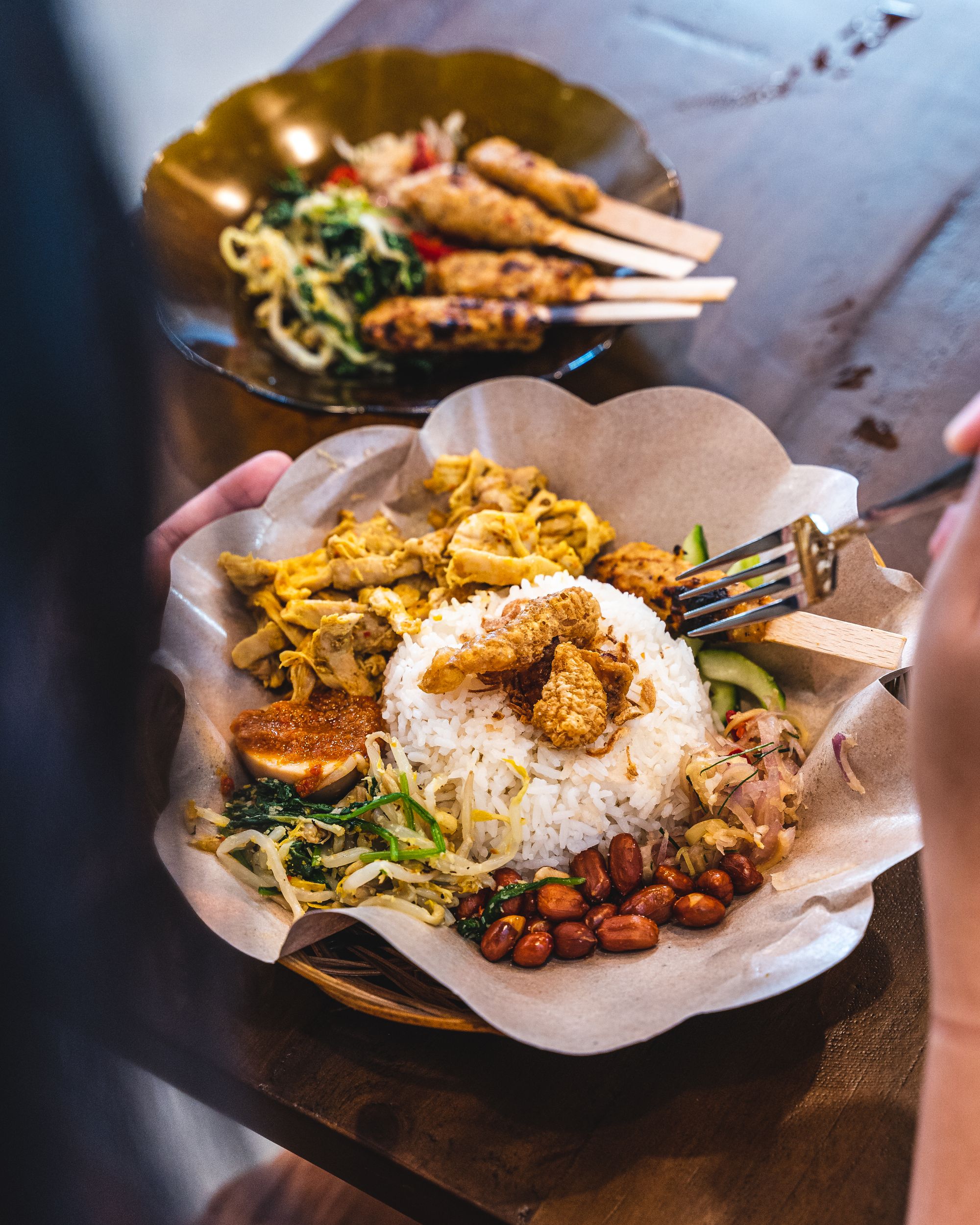 Close up shot of nasi bali with chikcen, vegetables and peanuts presented around a mound of rice