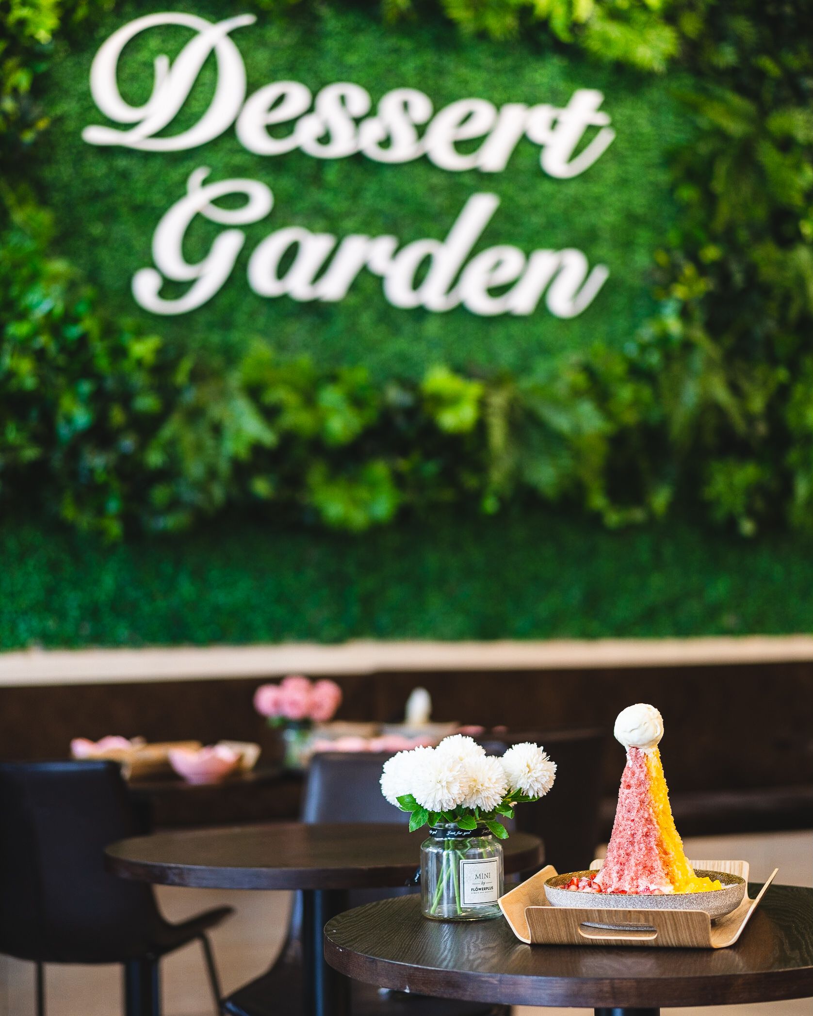 Shaved ice dessert placed on a table with the Dessert Garden sign in the background