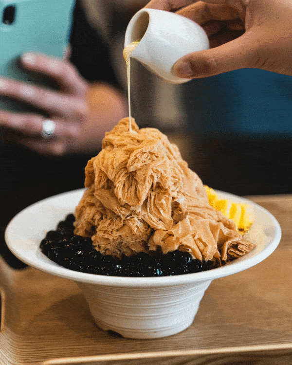 A stop motion video of a dessert in a bowl piled up high with sauce being drizzled ontop.