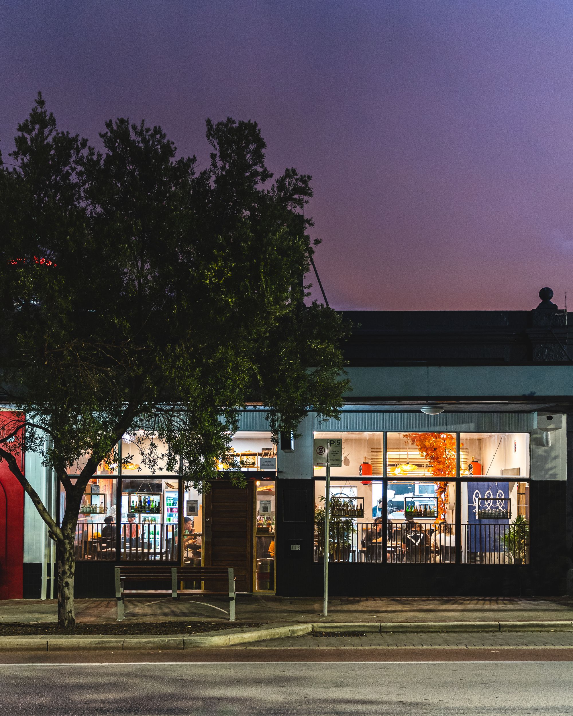 A front shot of Kukan Izakaya with a purple pink gradient sky