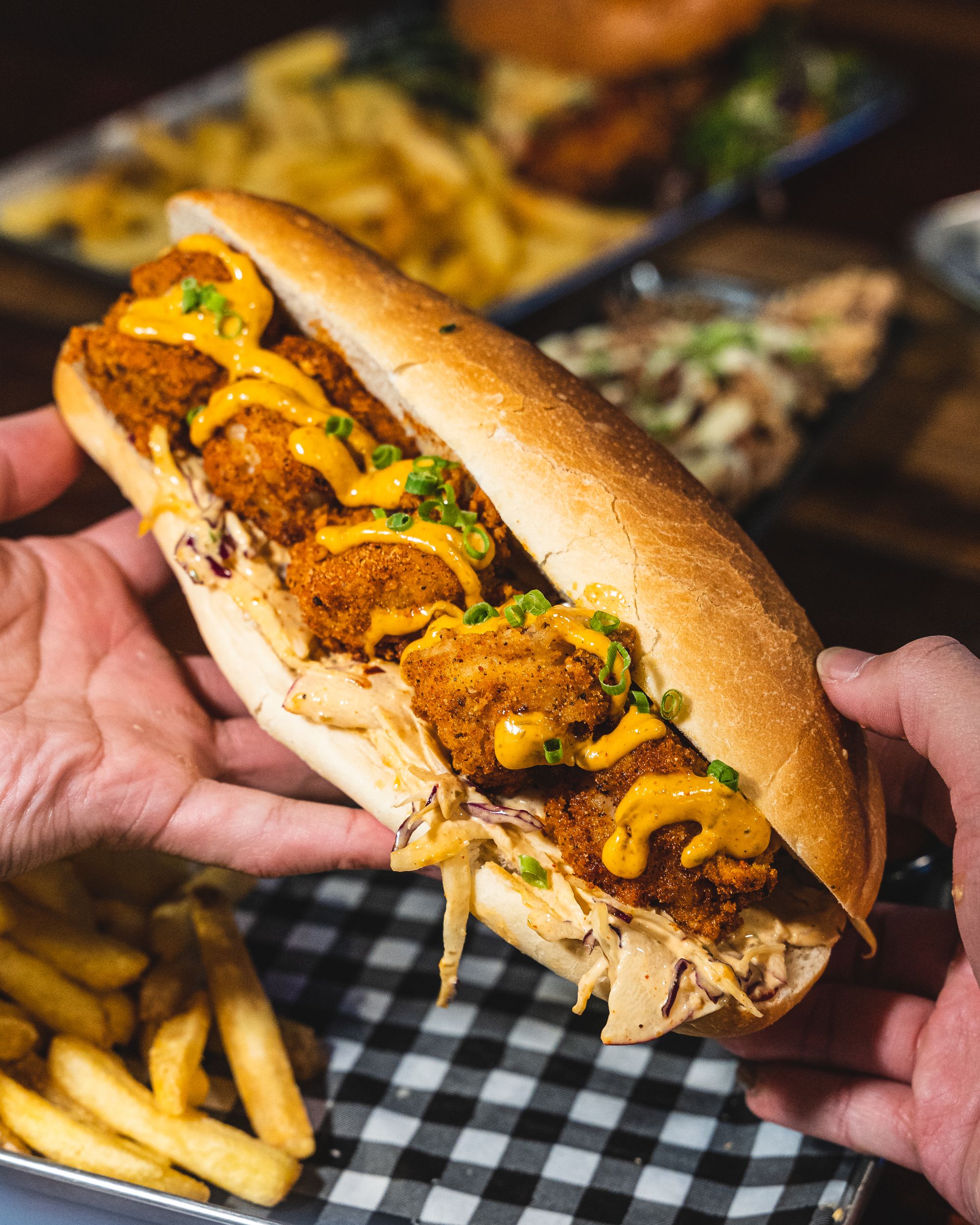 Handheld shot of a prawn po-boy, oozing with creamy remoulade.