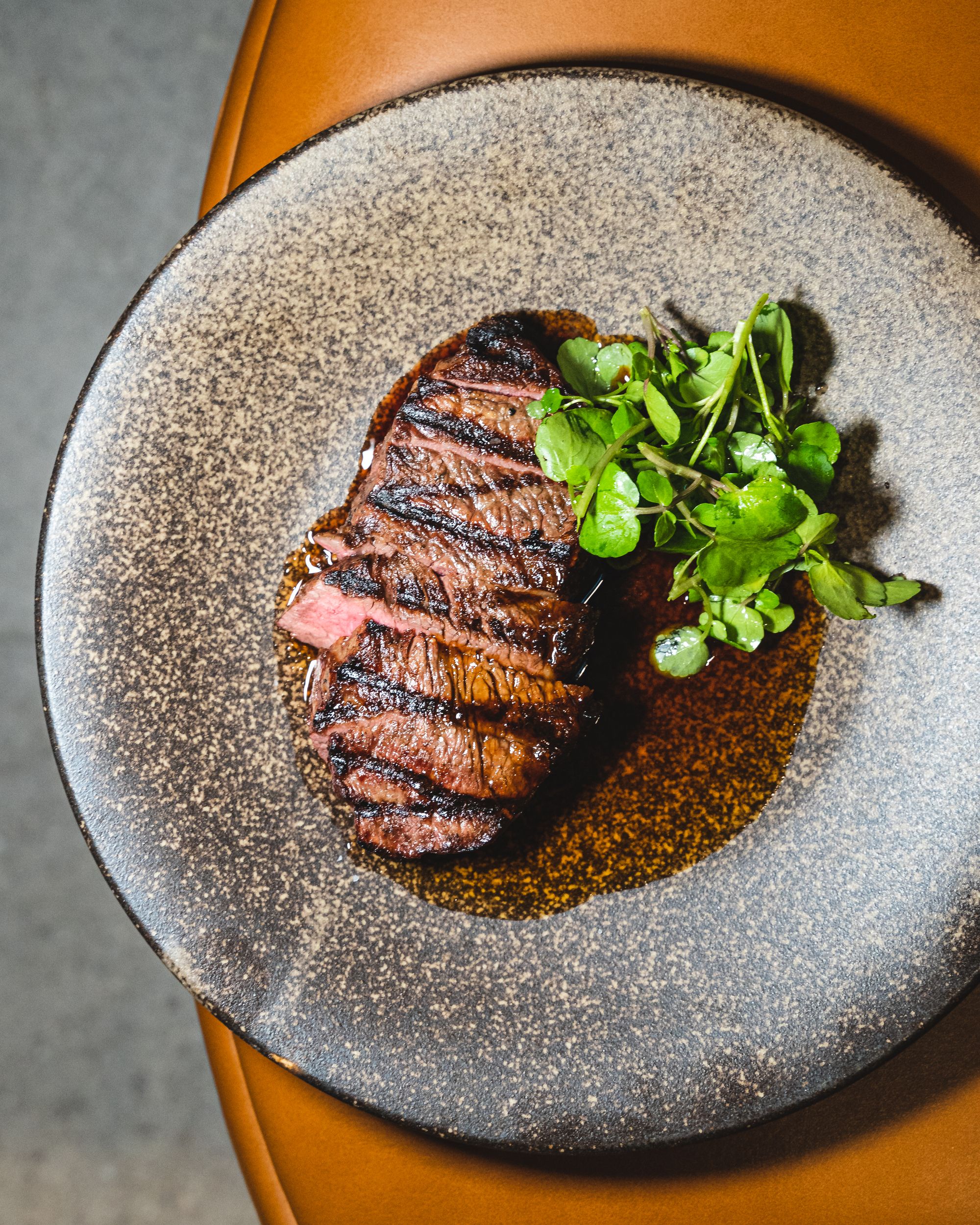 Top down of a well finished steak with a side of greens