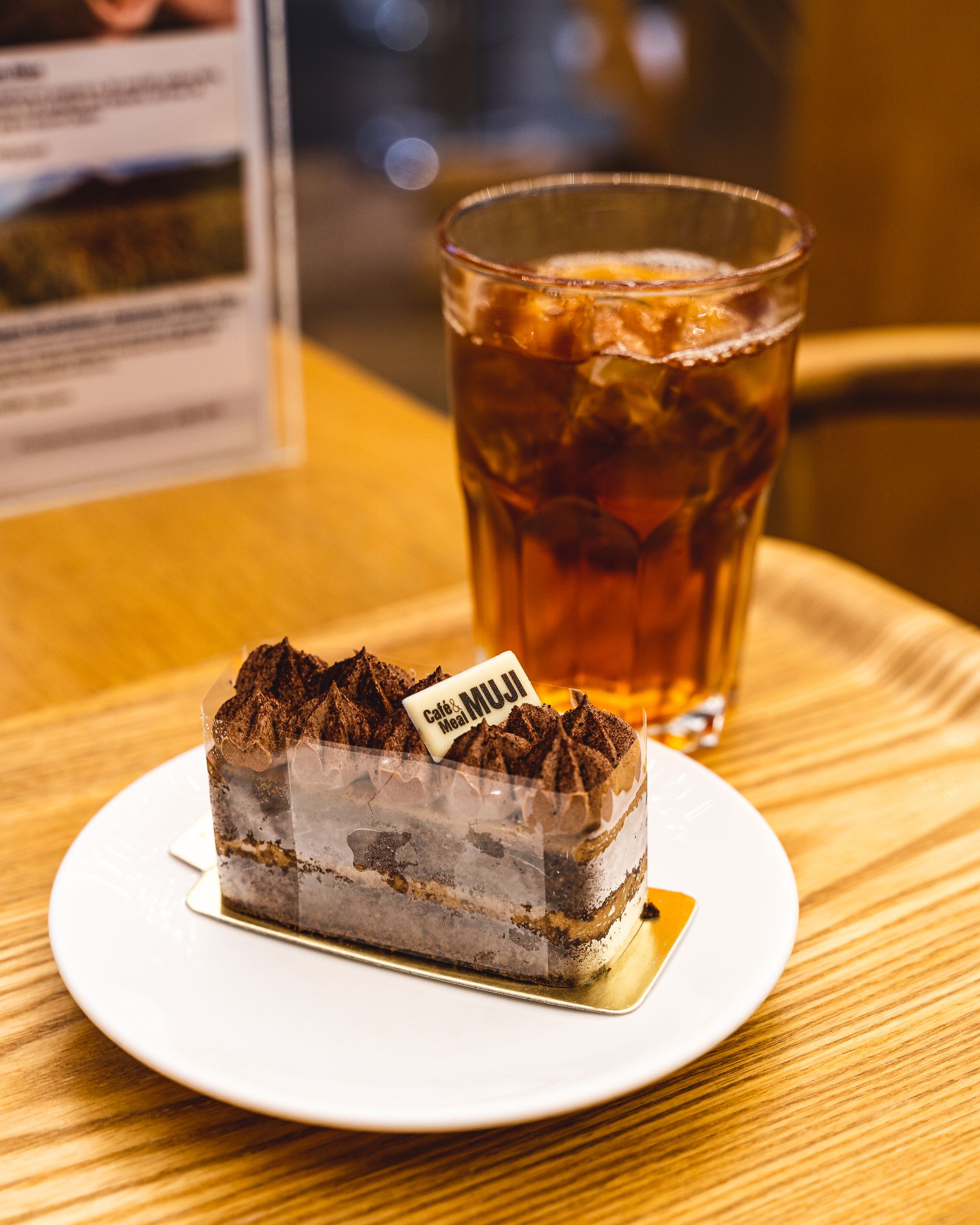 Chocolate cake on a plate with a glass of tea in the background