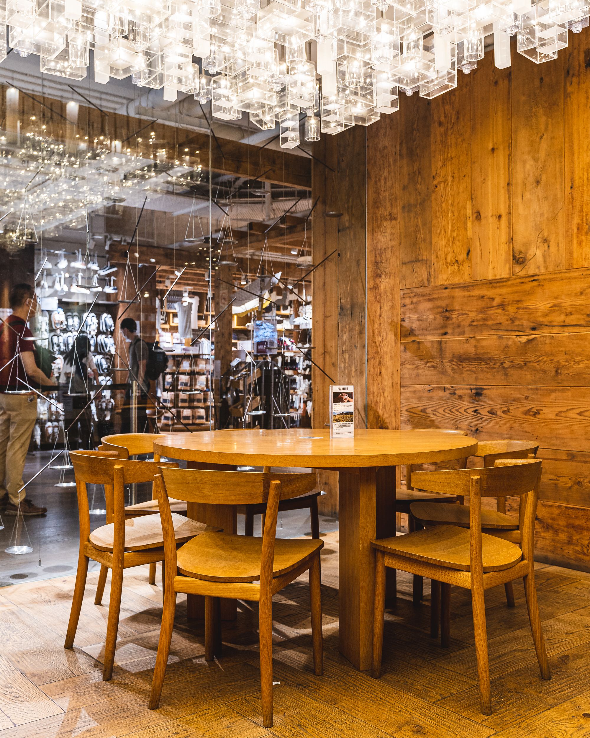 Interior shot of Muji showing a large, circular wooden desk and tables around it