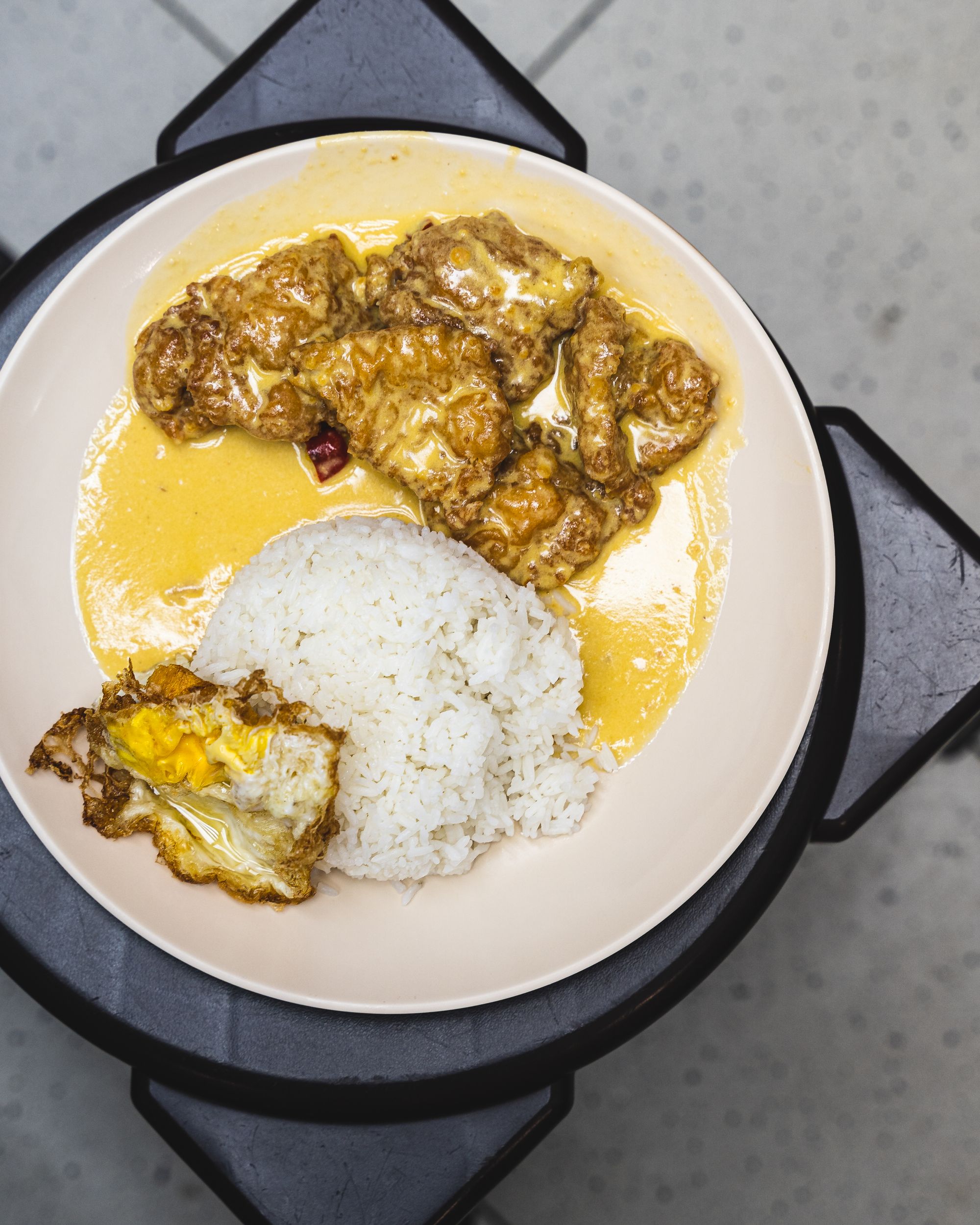 Birds eye shot of a plate with salted pork ribs, rice and a tried egg