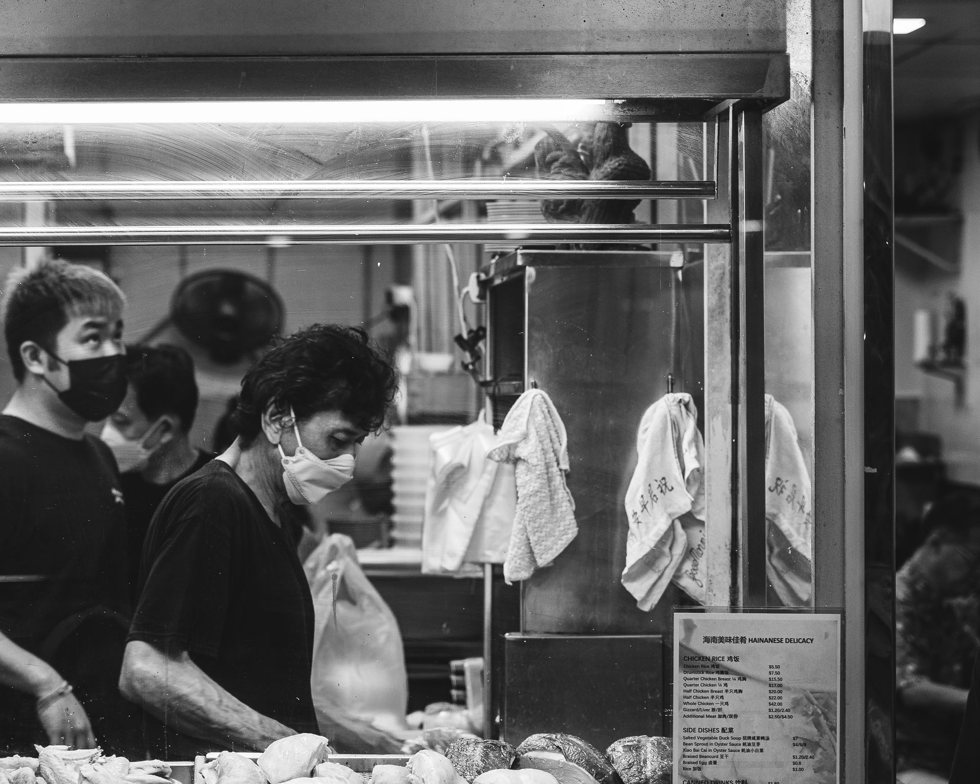 Black and white photo of staff in a kitchen chopping up chicken