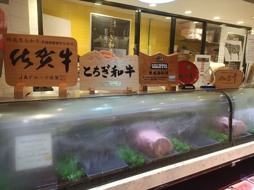 Close up of butcher fridge with a number of Japanese signs showing different brands of wagyu