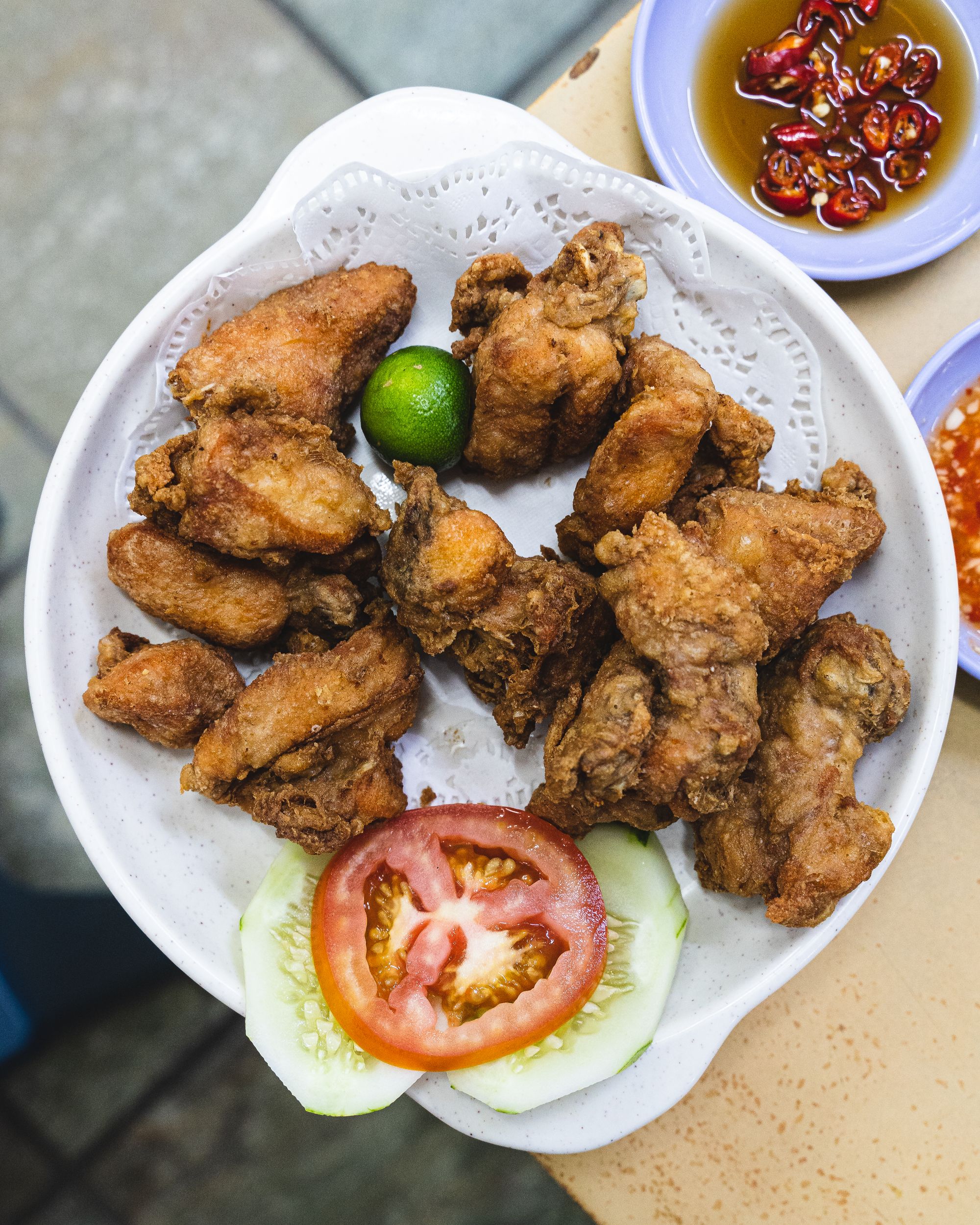 Close up of fried chicken pieces and a calamansi, cucumber and tomato as garnish