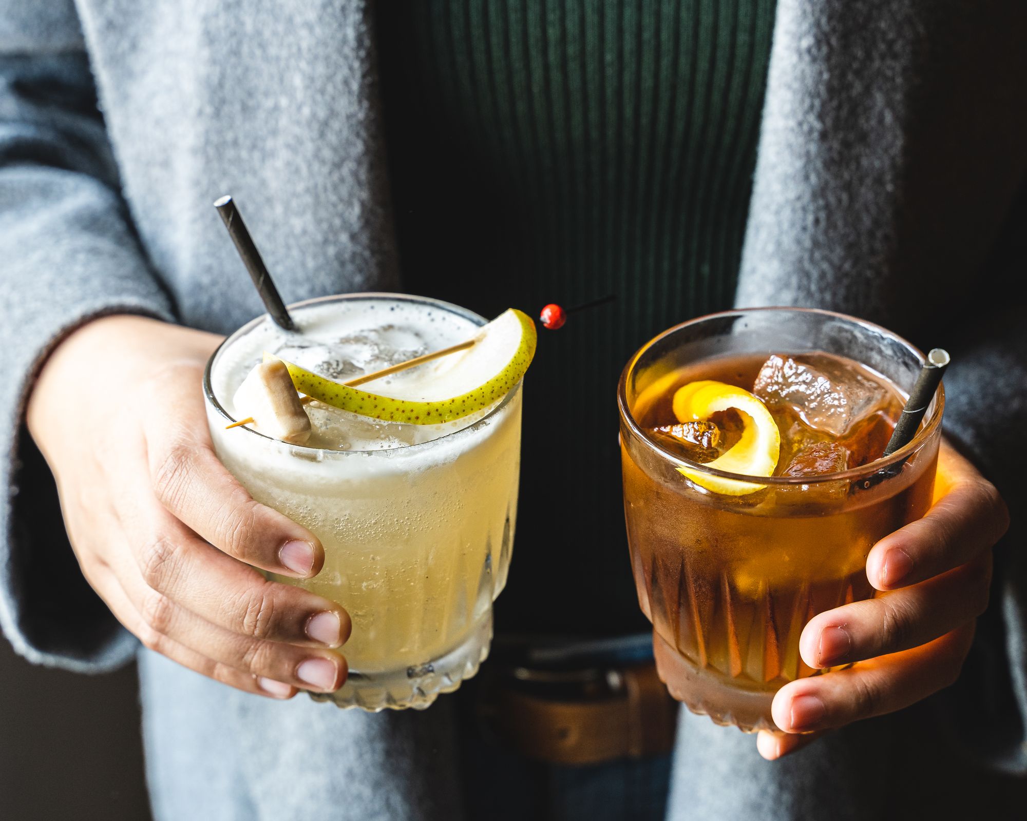 Close up shot of two hands holding two cocktails