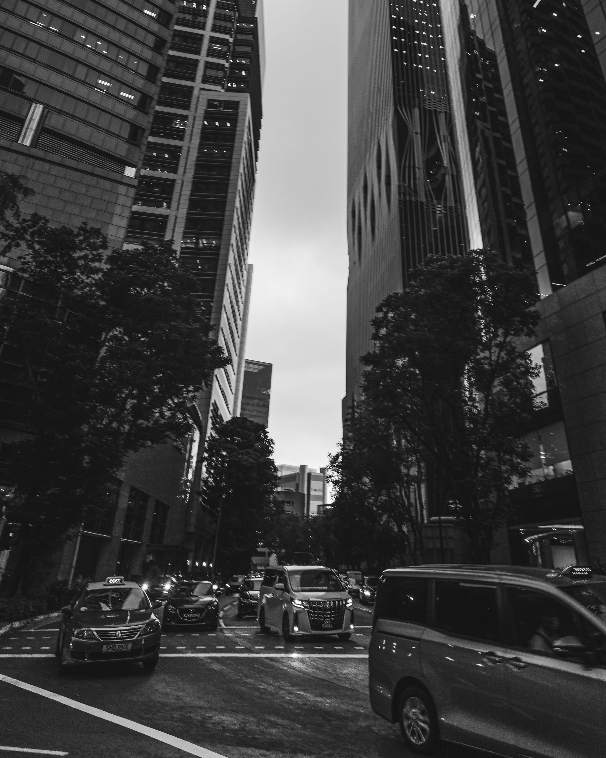 Black and white image of cars driving through a busy street in the CBD