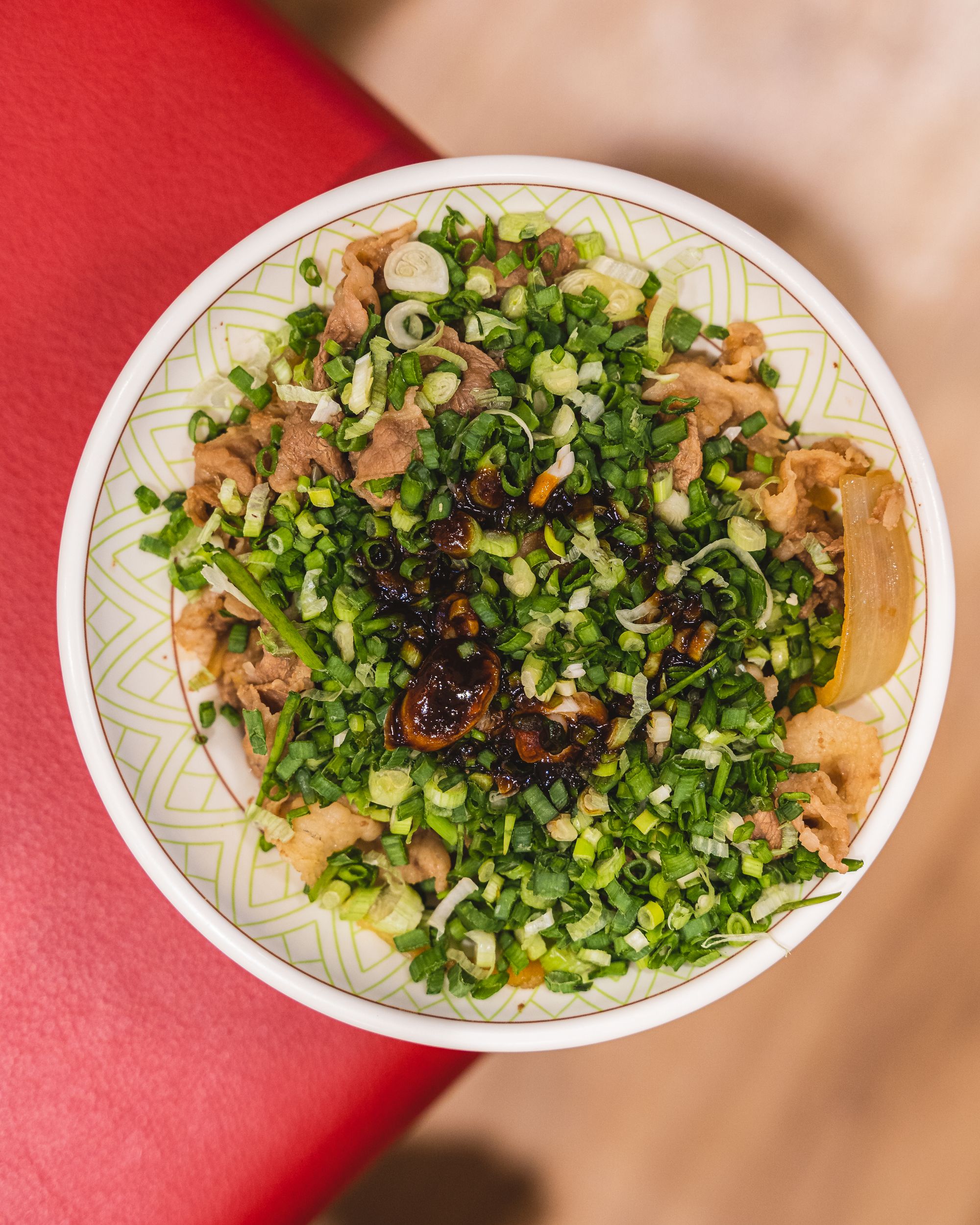 Overhead view of gyudon with spring onion and half boiled egg