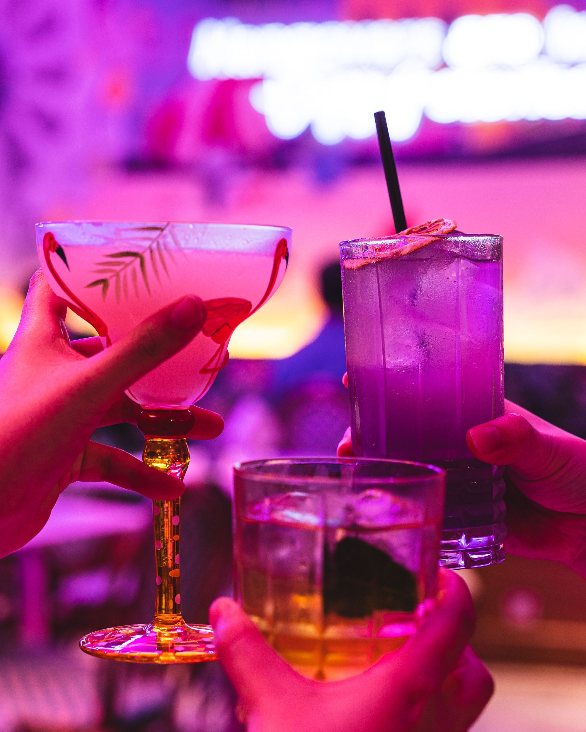 Three cocktail glasses held in hands cheersing