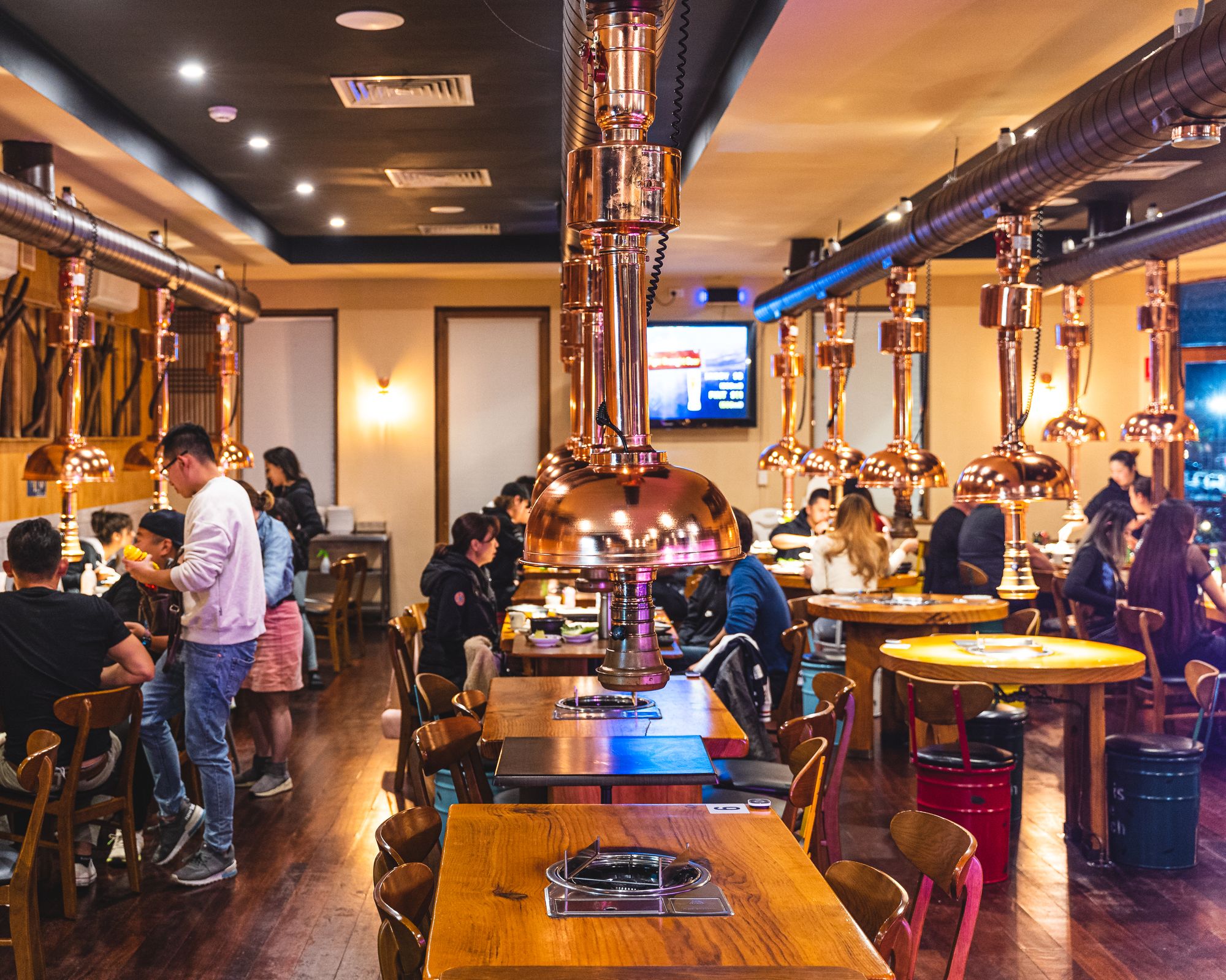 A bustling Korean BBQ restaurant with overhanging exhaust fans