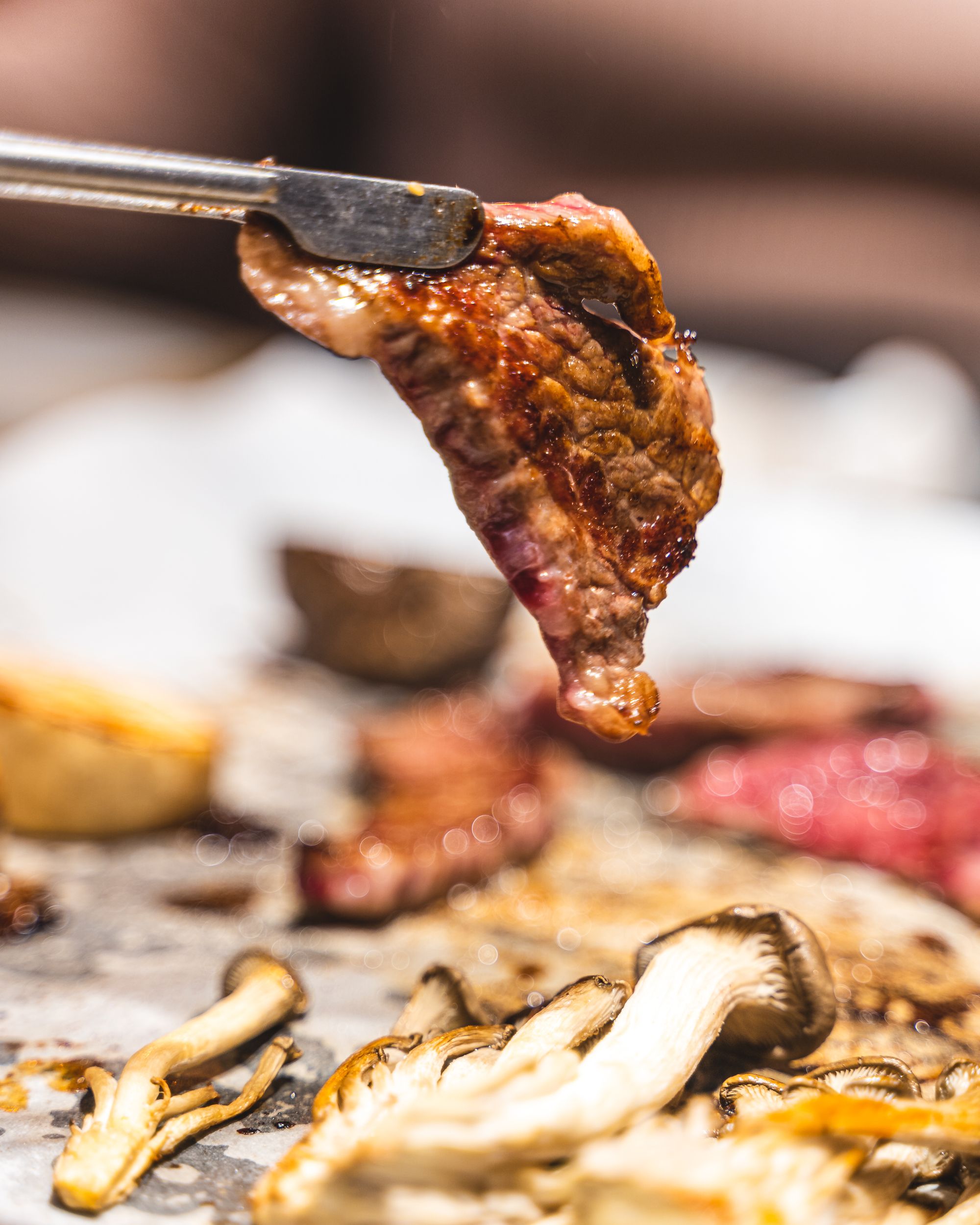 Close up shot of grilled meat being held by tweezes