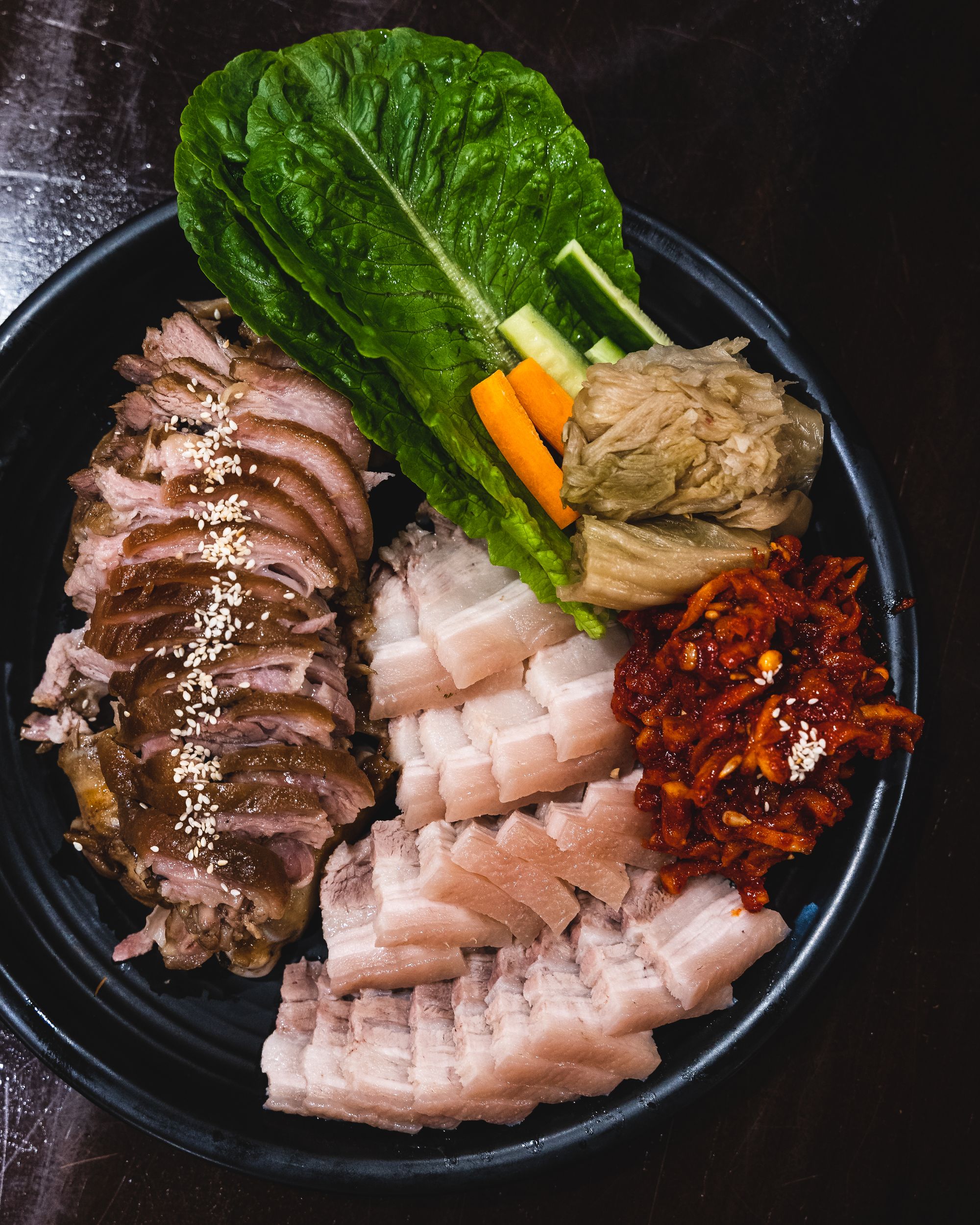 Korean bossam with sliced pork shoulder and fermented vegetables and leafy greens