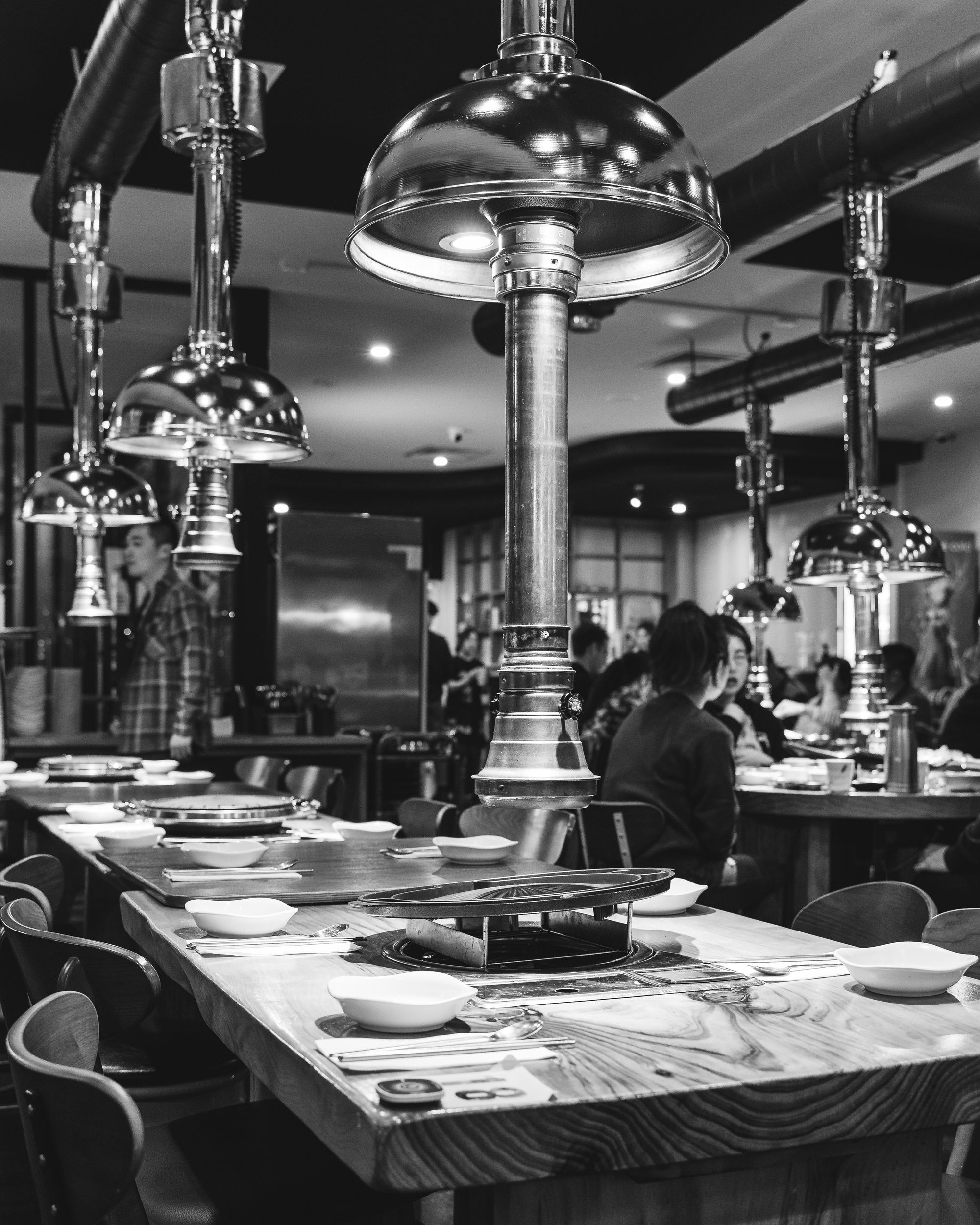 Black and white photo of Korean BBQ restaurant interior, with exhaust fans