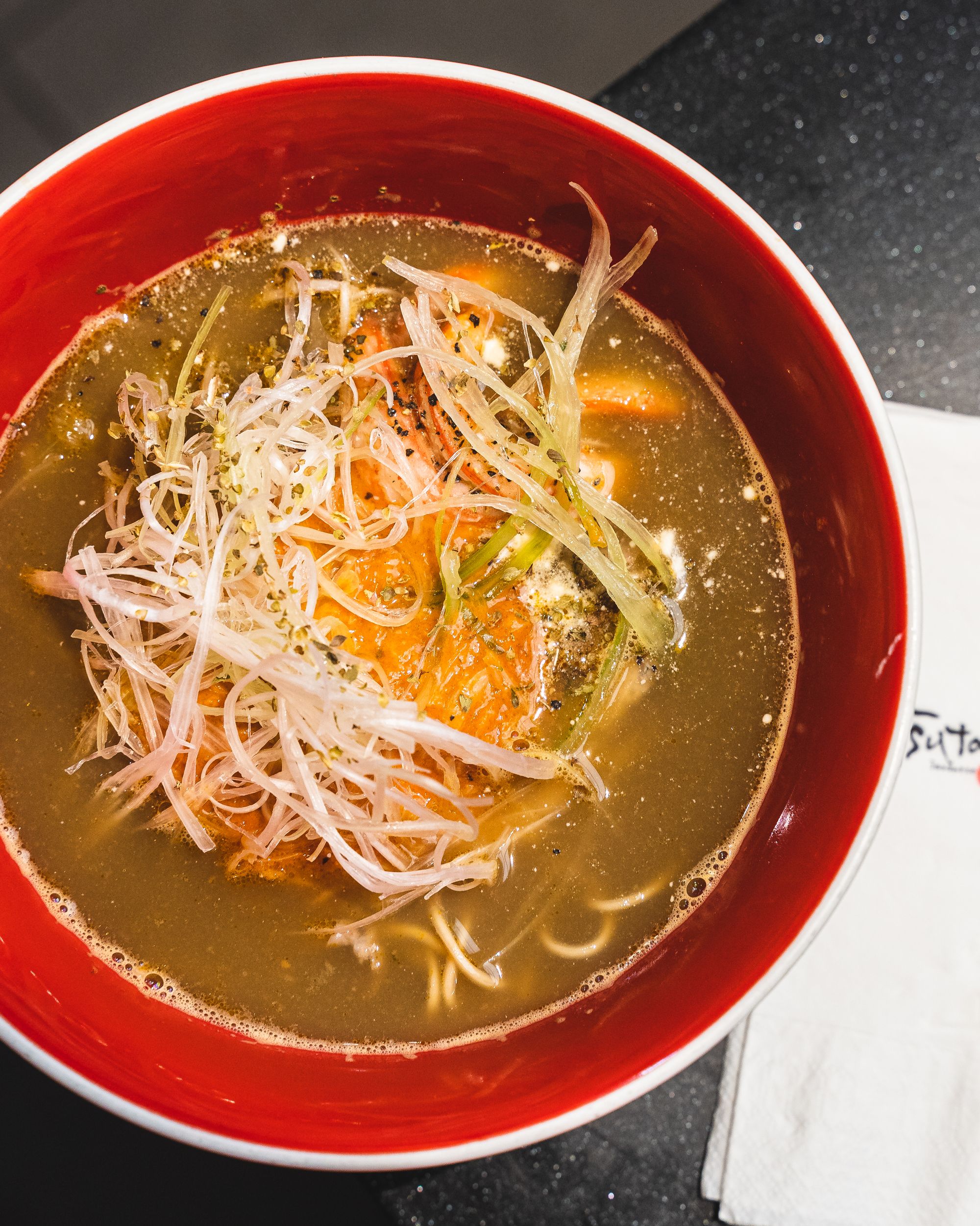 Top down shop of a bowl of crab ramen with a Tsuta branded napkin on the side