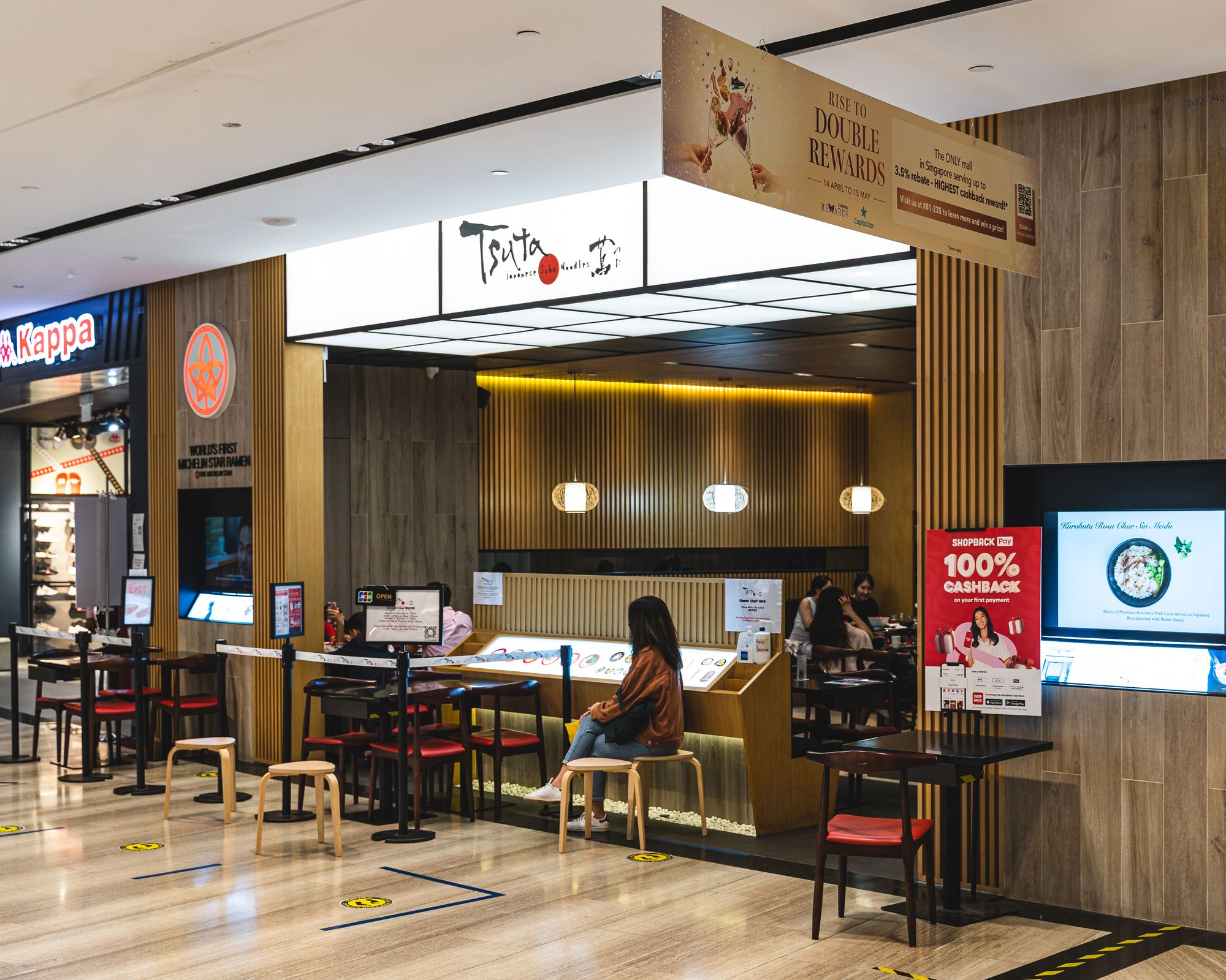 Exterior of Tsuta showing a lady sitting in-front and customers sitting inside