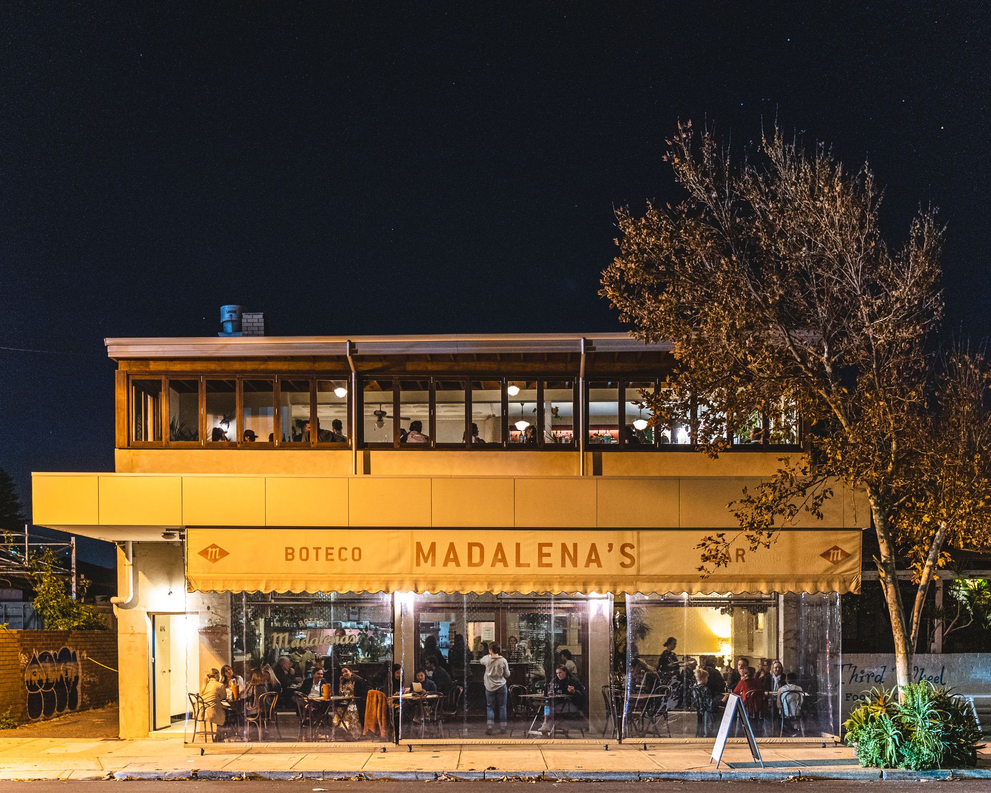 Exterior shot of a double story restaurant with alfresco dining and an upstairs bar