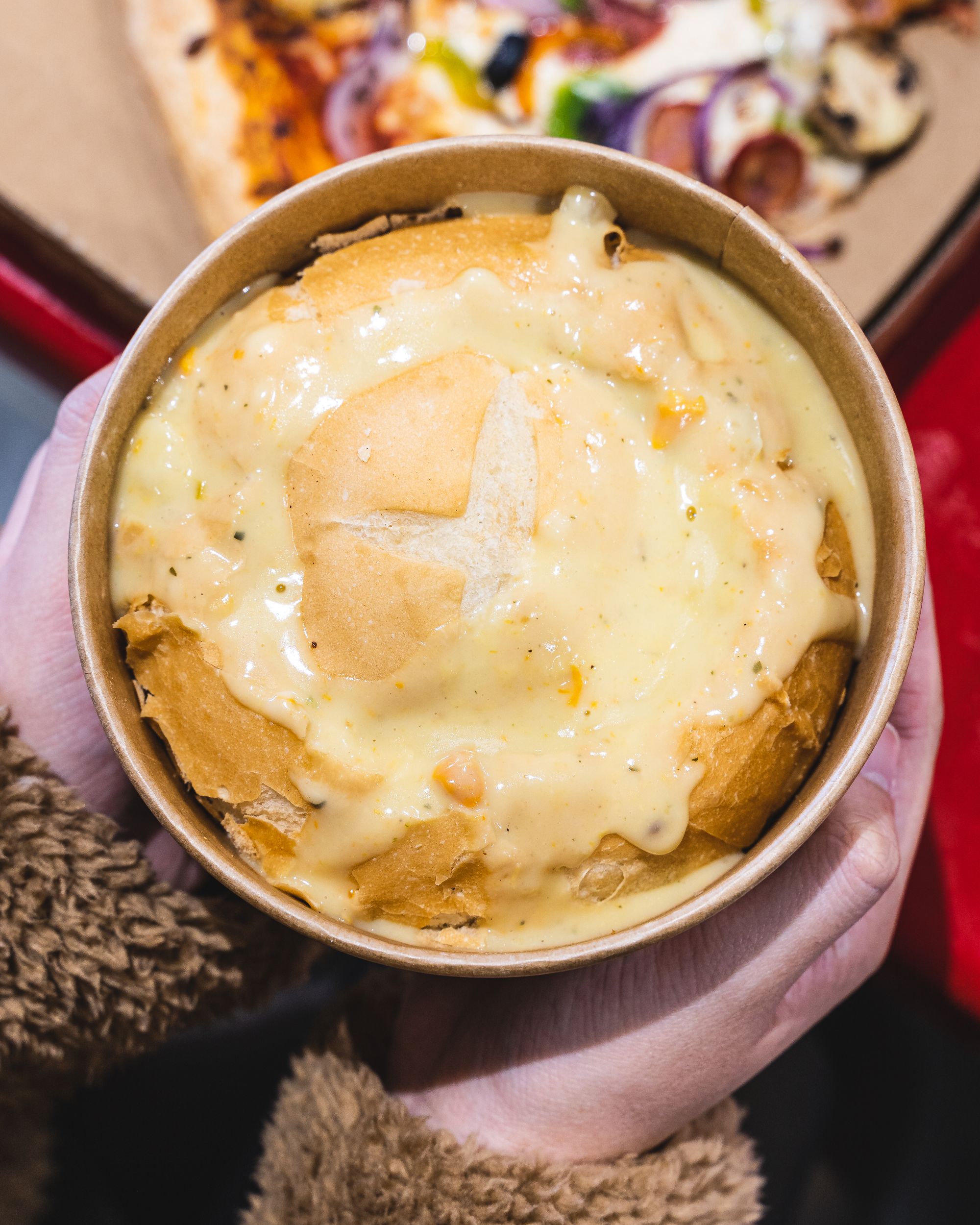 Overhead shot of hand holding a bread bun filled with chowder