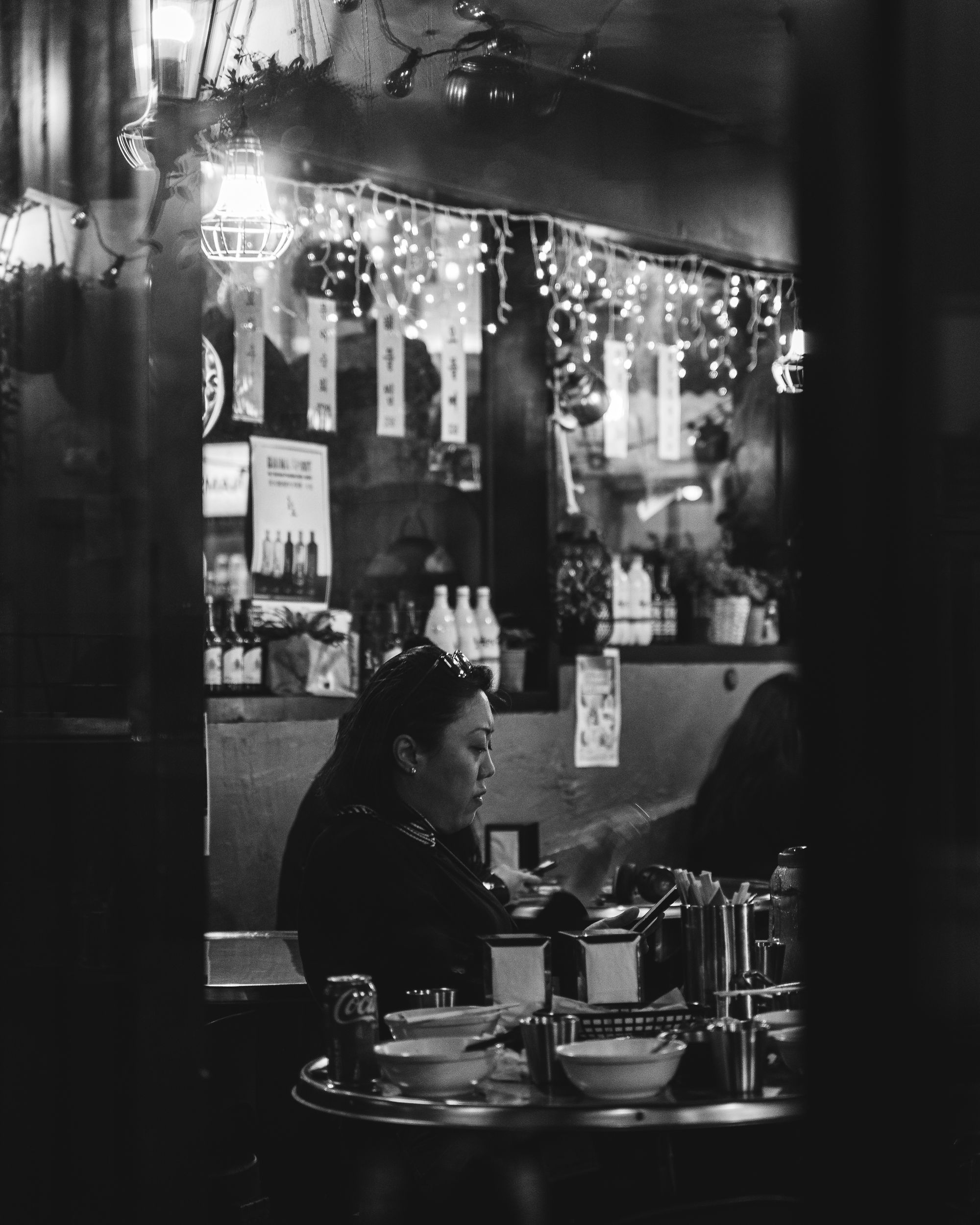 Black and white photo of a lady on her phone inside the interior of Namsan