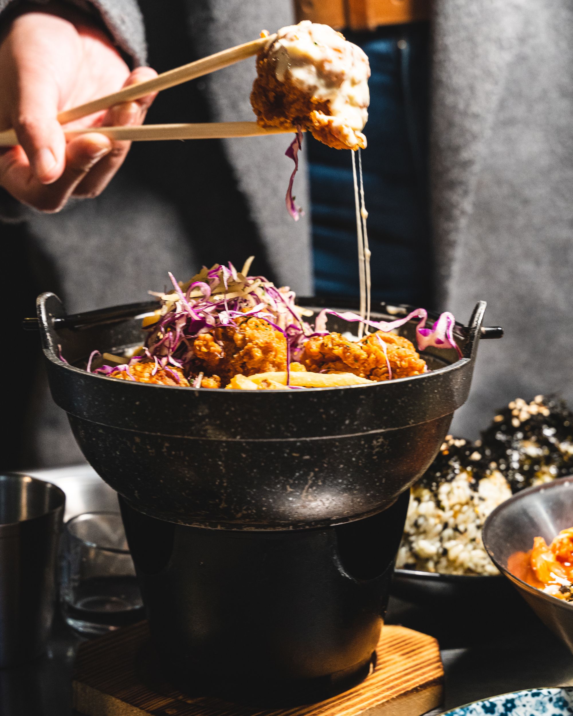 Close up of cheese fried chicken pieces being lifted up with chopsticks