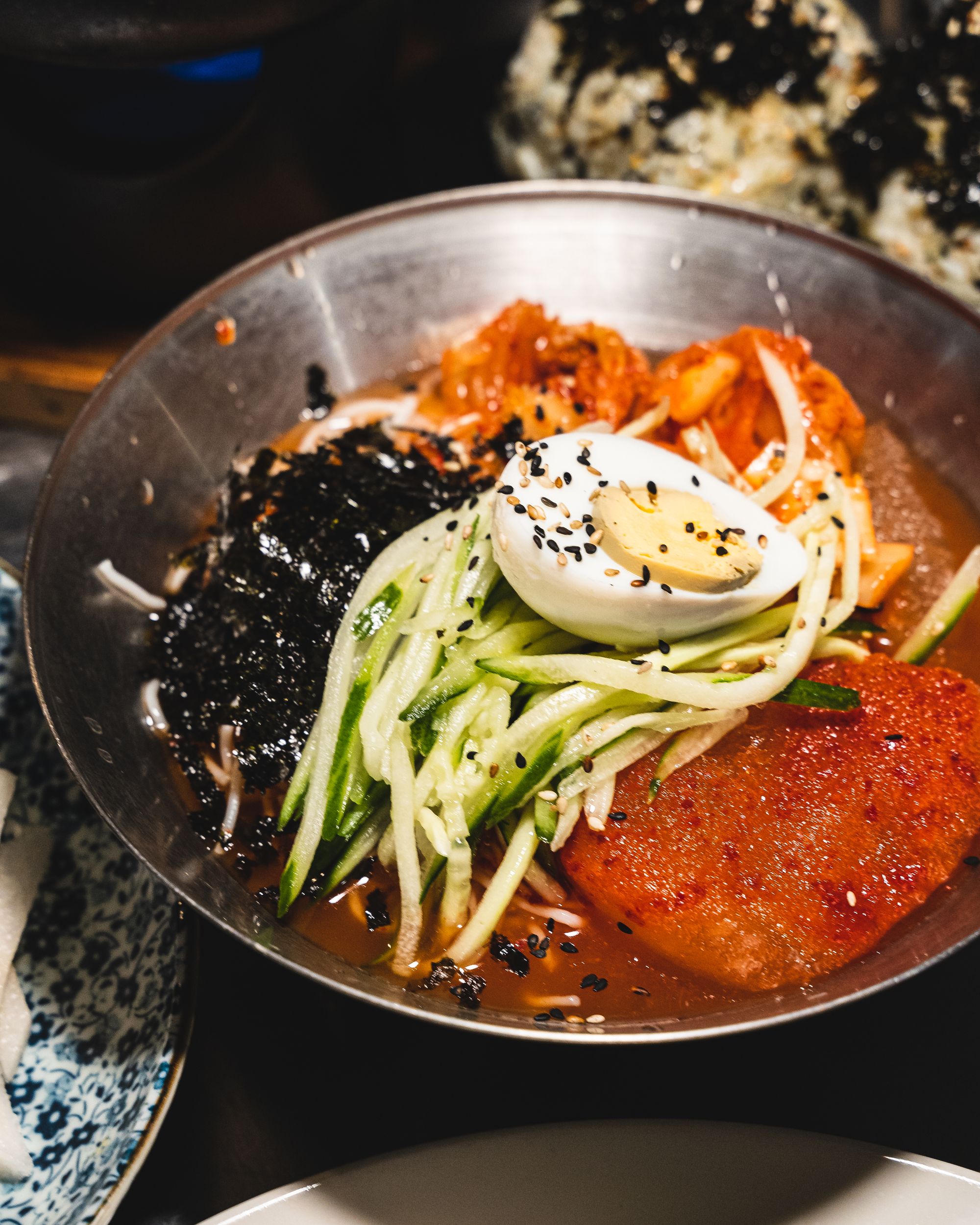 Close up of Korean cold noodles garnished with egg and thinly sliced cucumber