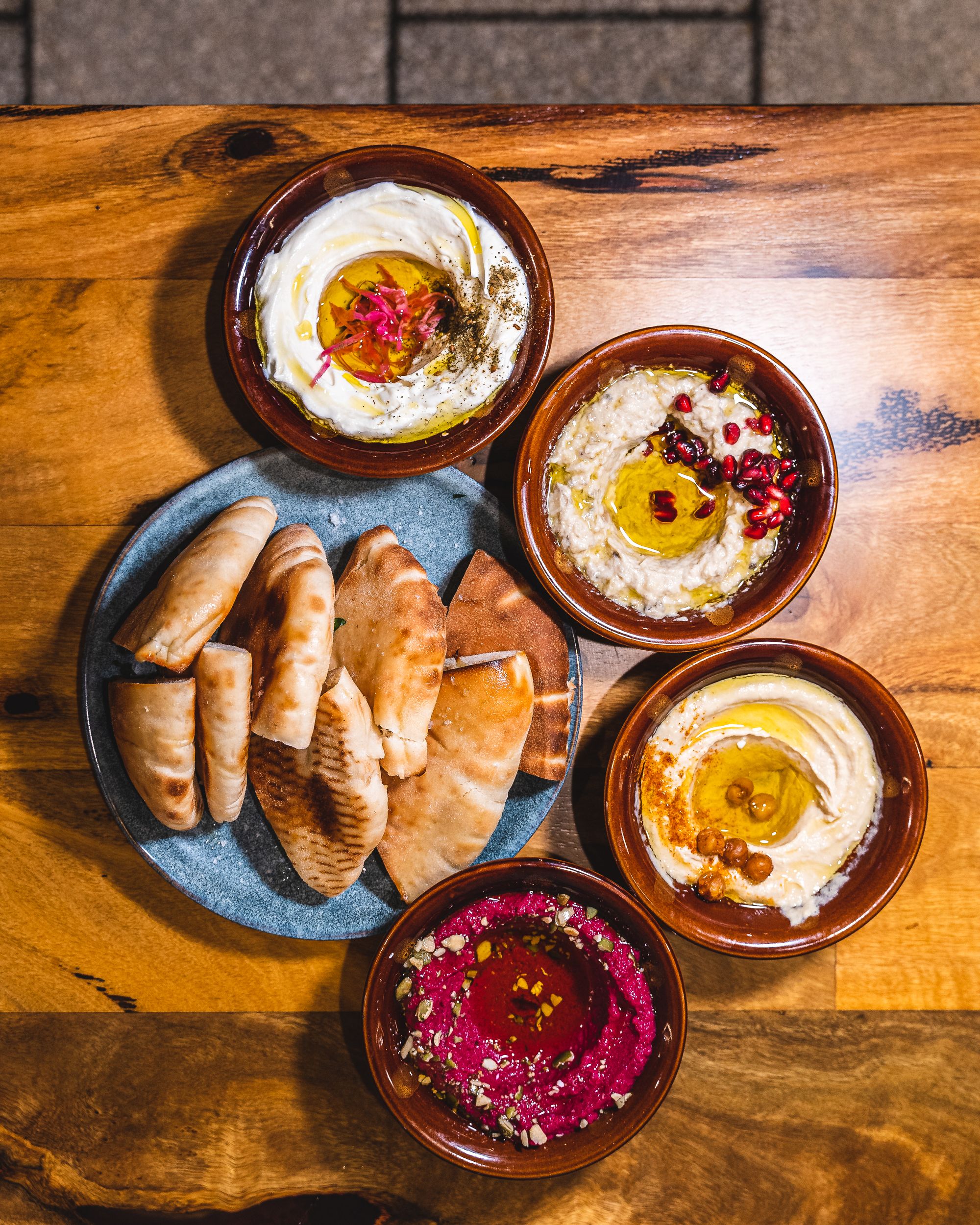 Top down of flat bread surrounded by different bowls of middle eastern dip