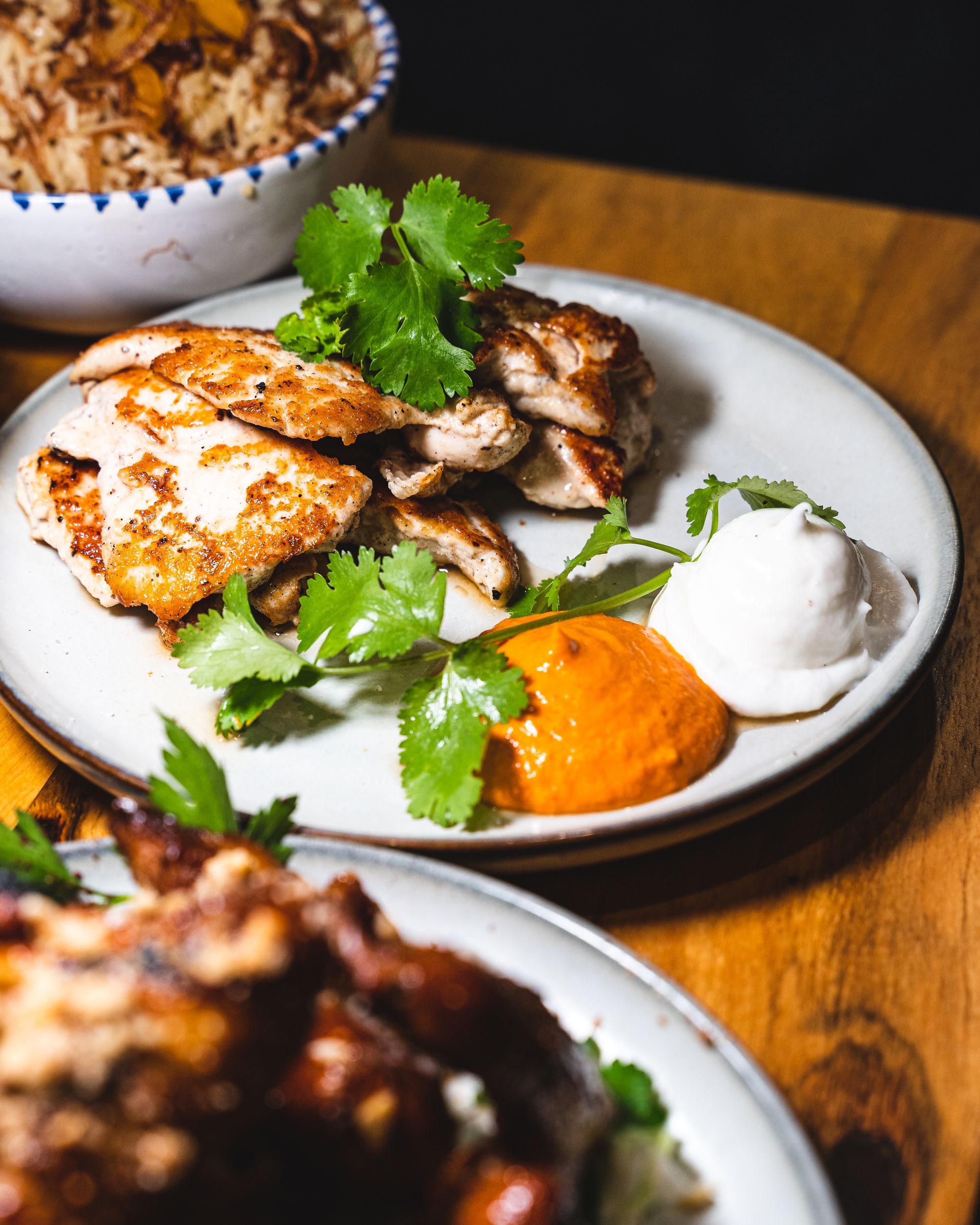 Close up of chicken dish with harissa, garlic sauce and coriander garnish