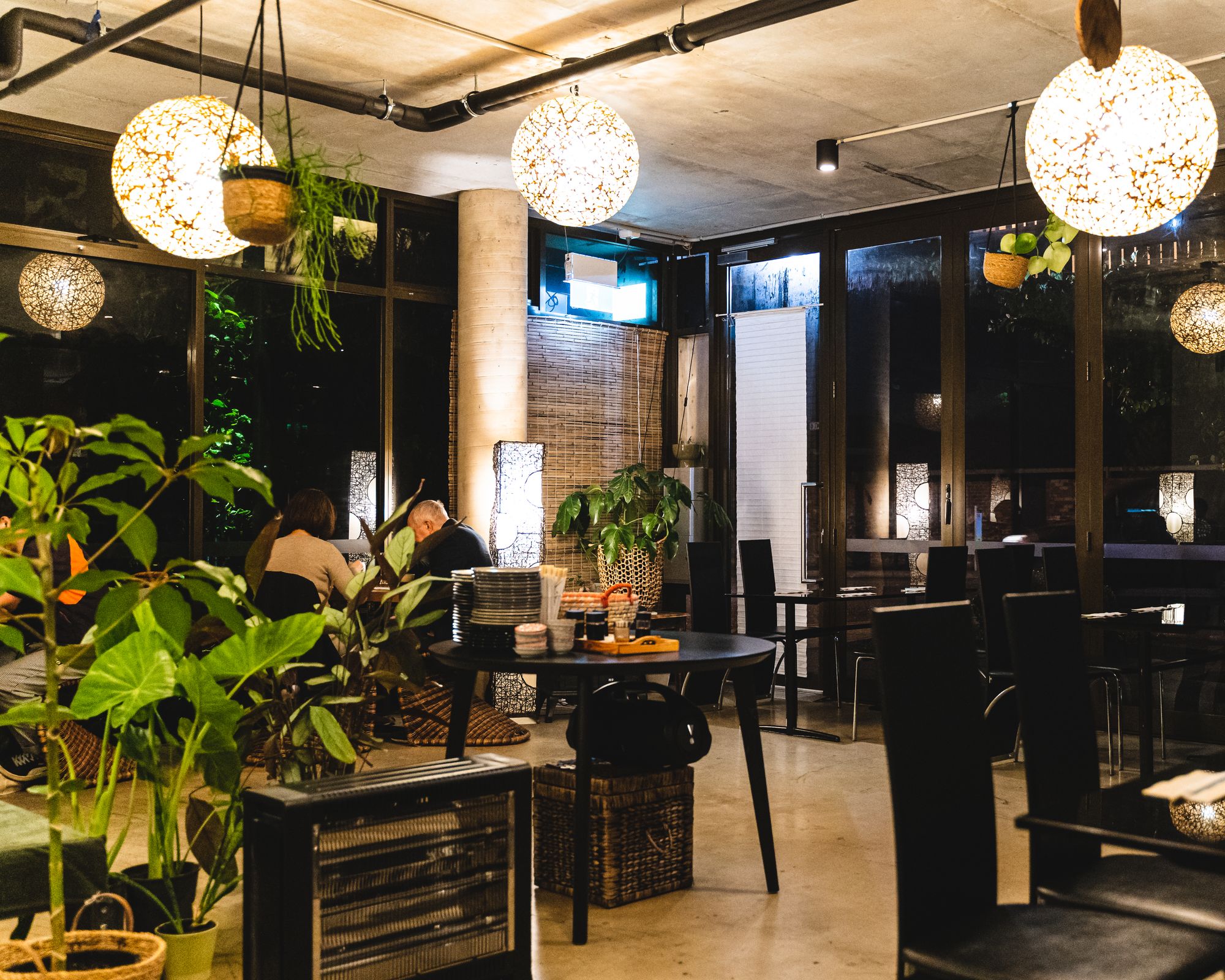 Interior of Sanco at night, showing exposed concrete and lots of green plants