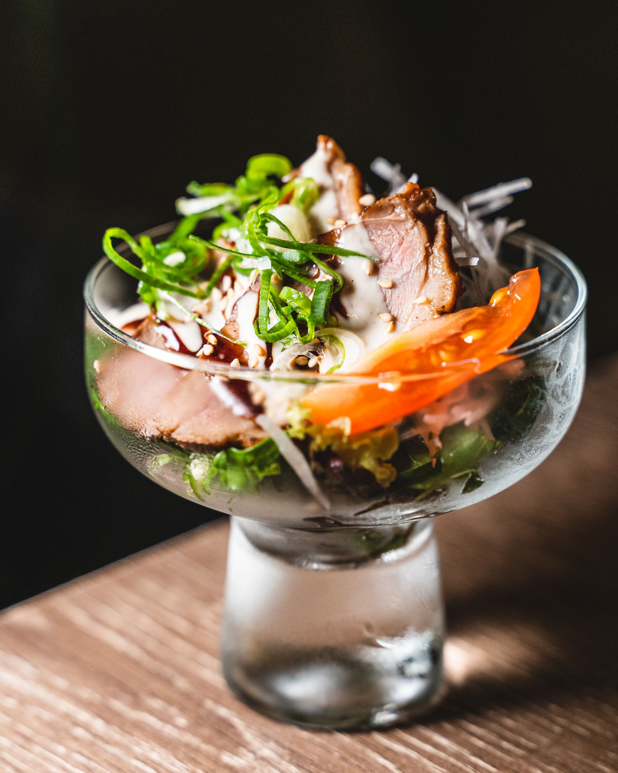 Close up of sliced roasted and braised duck with salad, served in a chilled clear glass