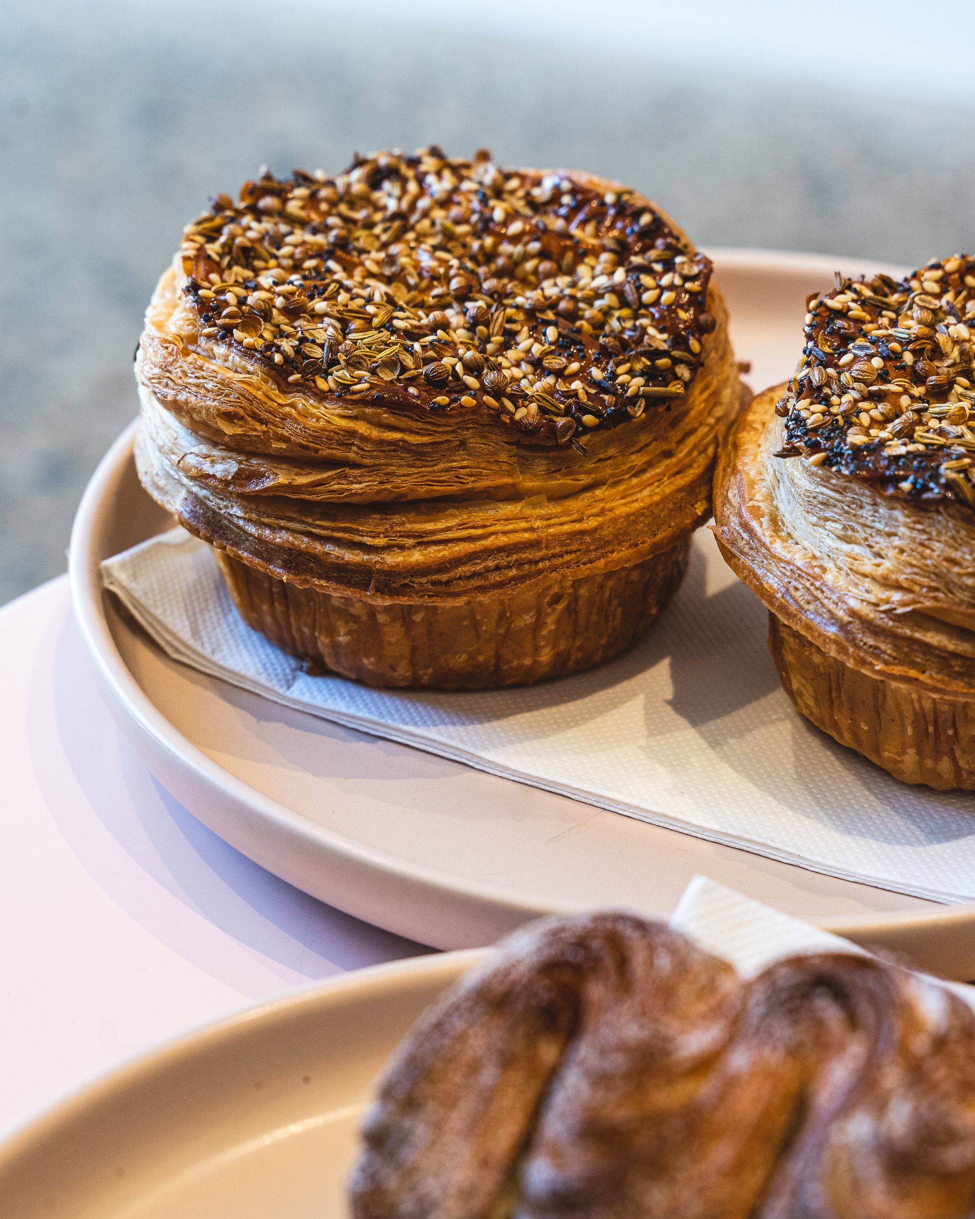 A pie showing many intricate layers which is topped with seasame seeds 