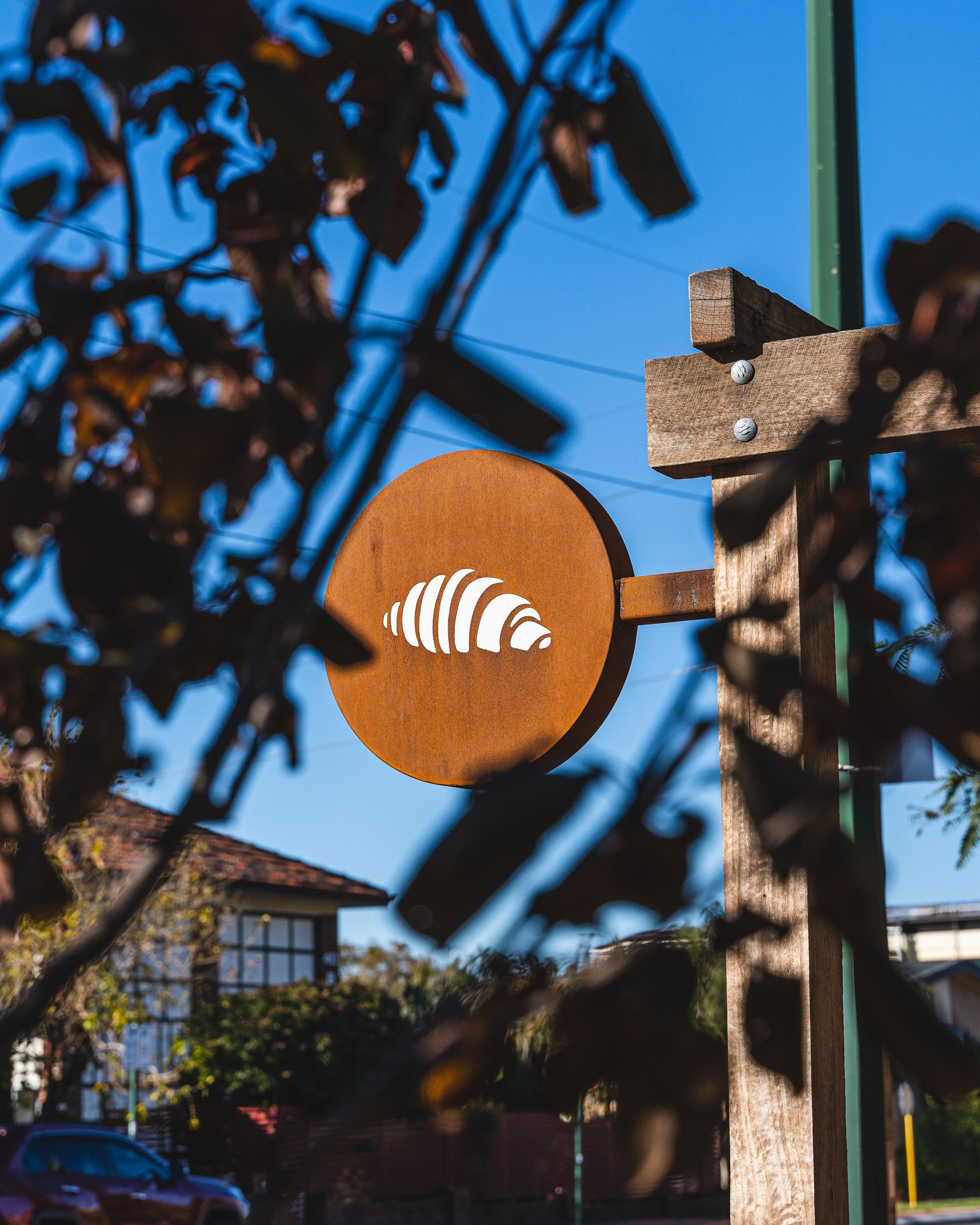 Croissant logo framed by tree leaves