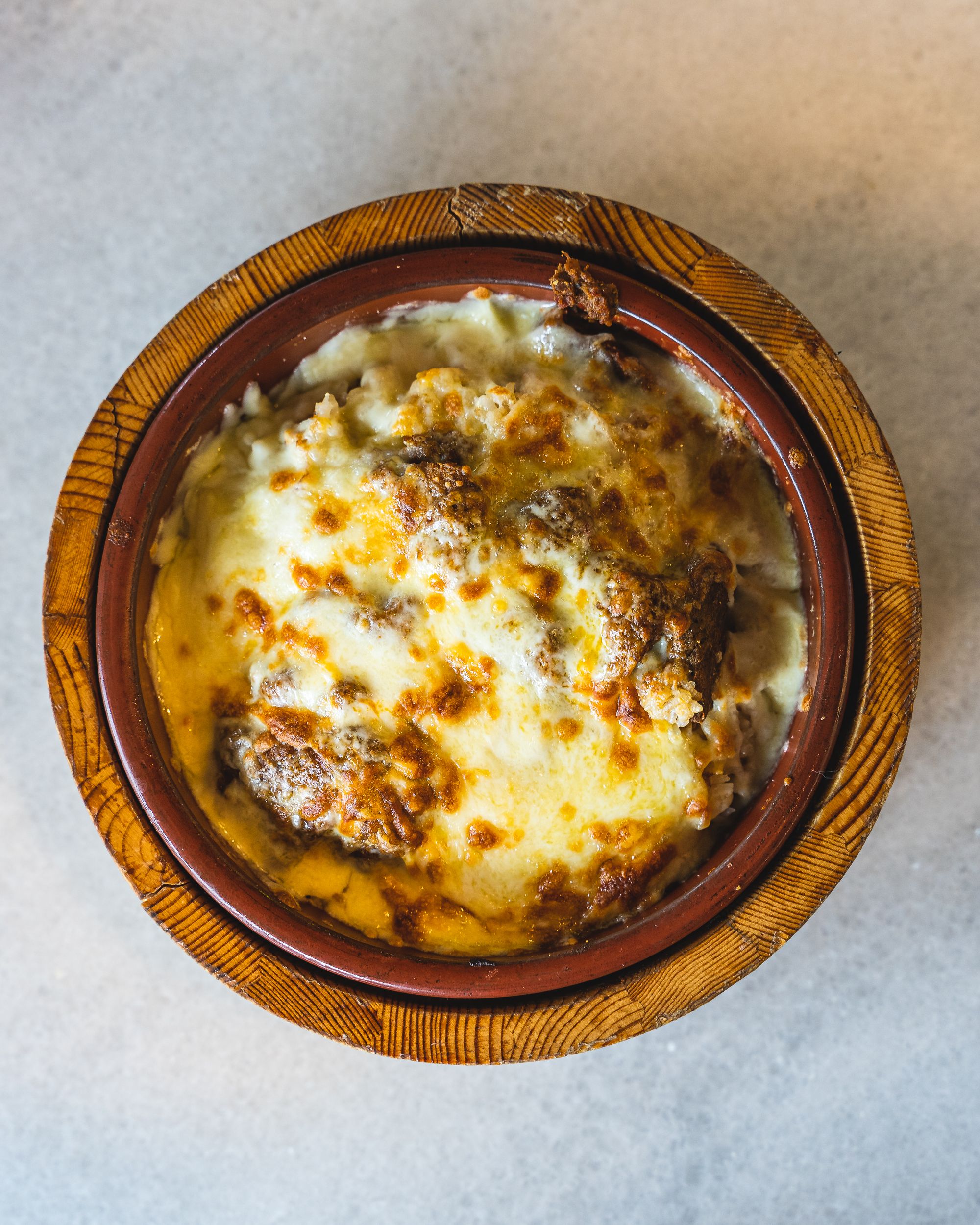 Top down shot of a cheese covered baked rice dish with beef rendang showing