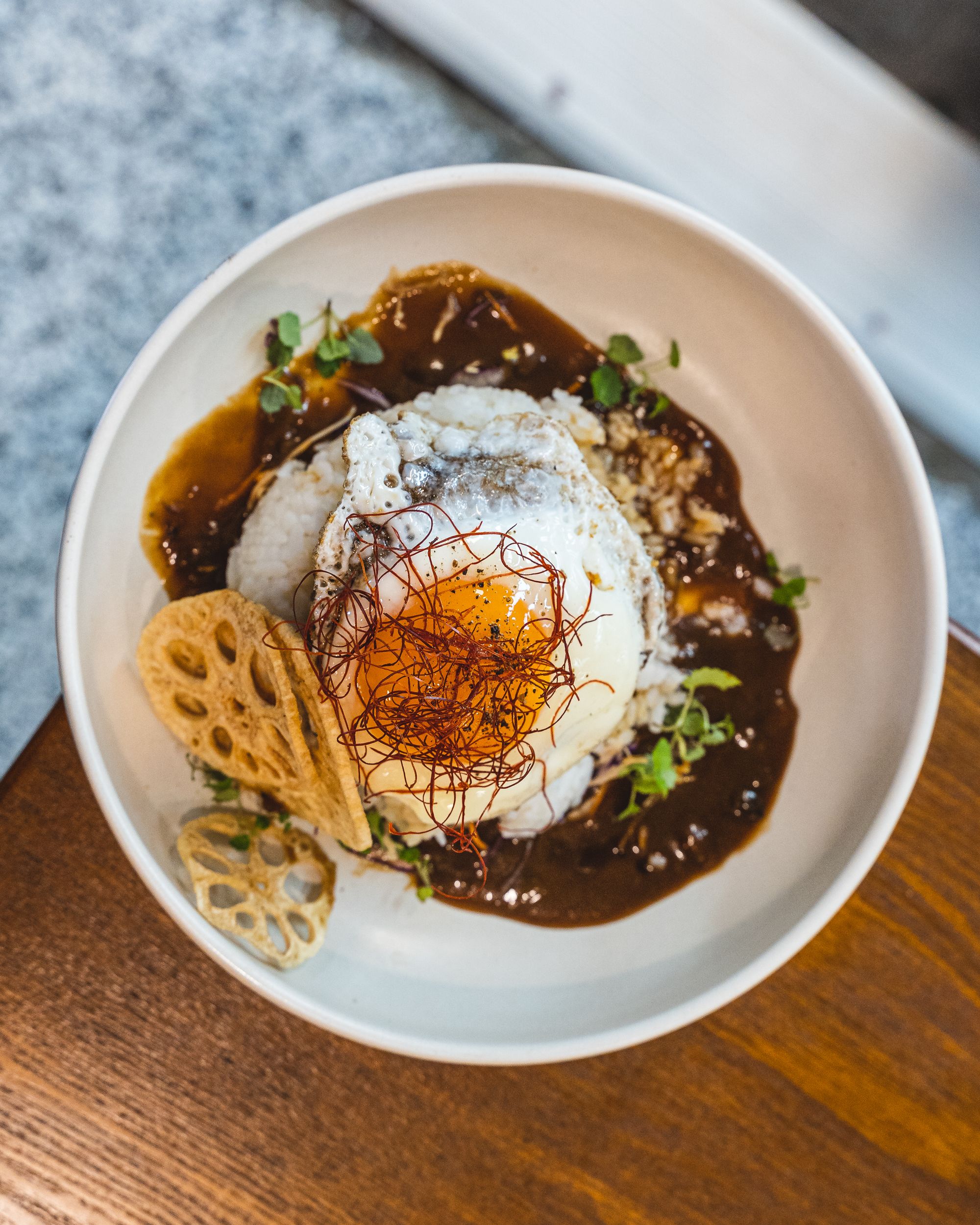 Top down of egg on-top of loco moco with sauce and lotus chips