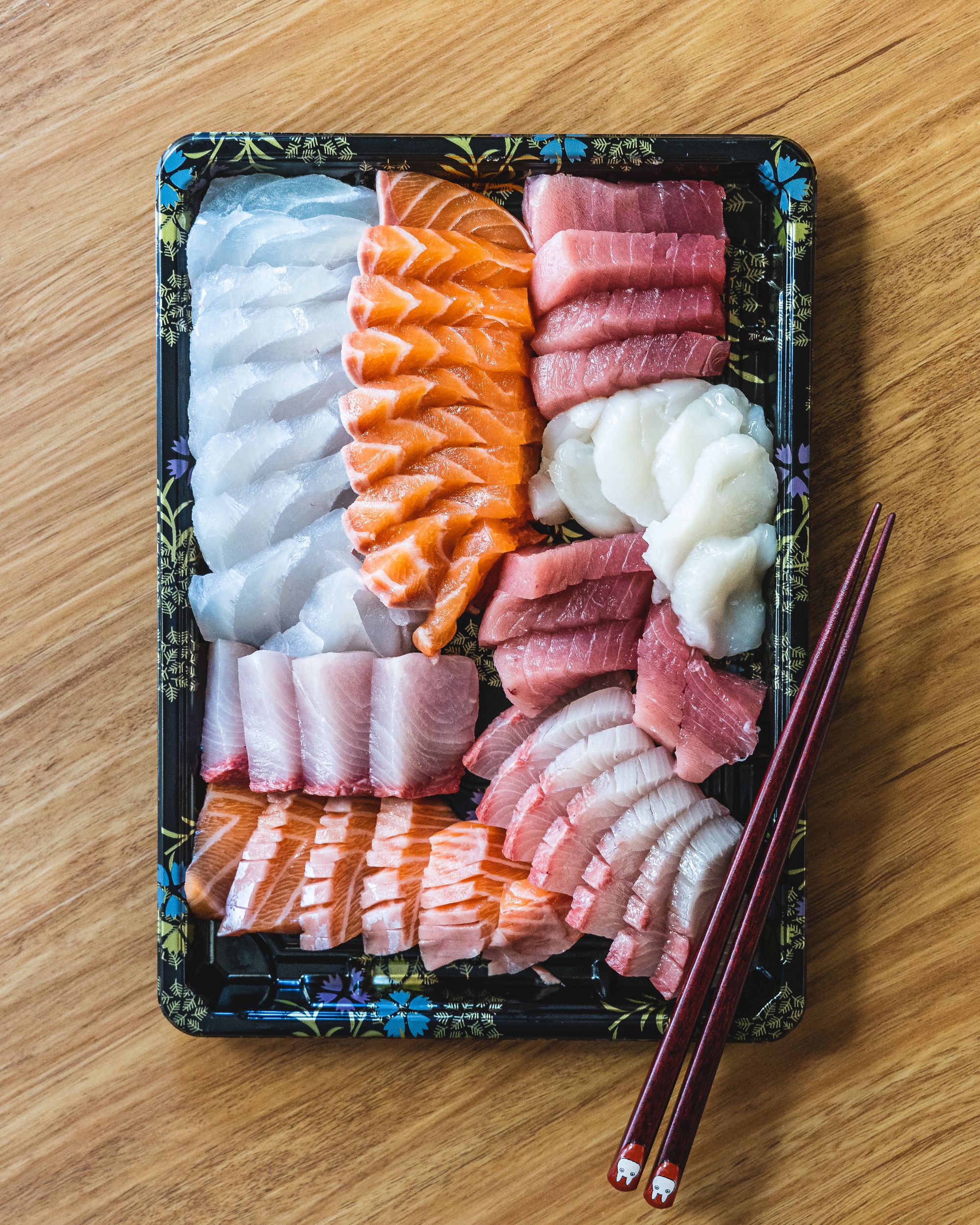 Close up of a colourful sashimi platter with chopsticks resting across in a corner