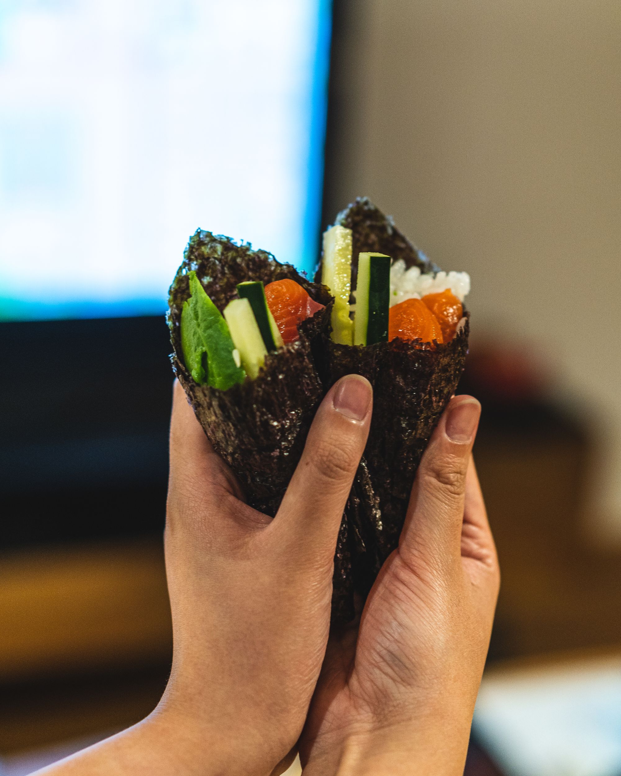 Hands holding handroll sushi