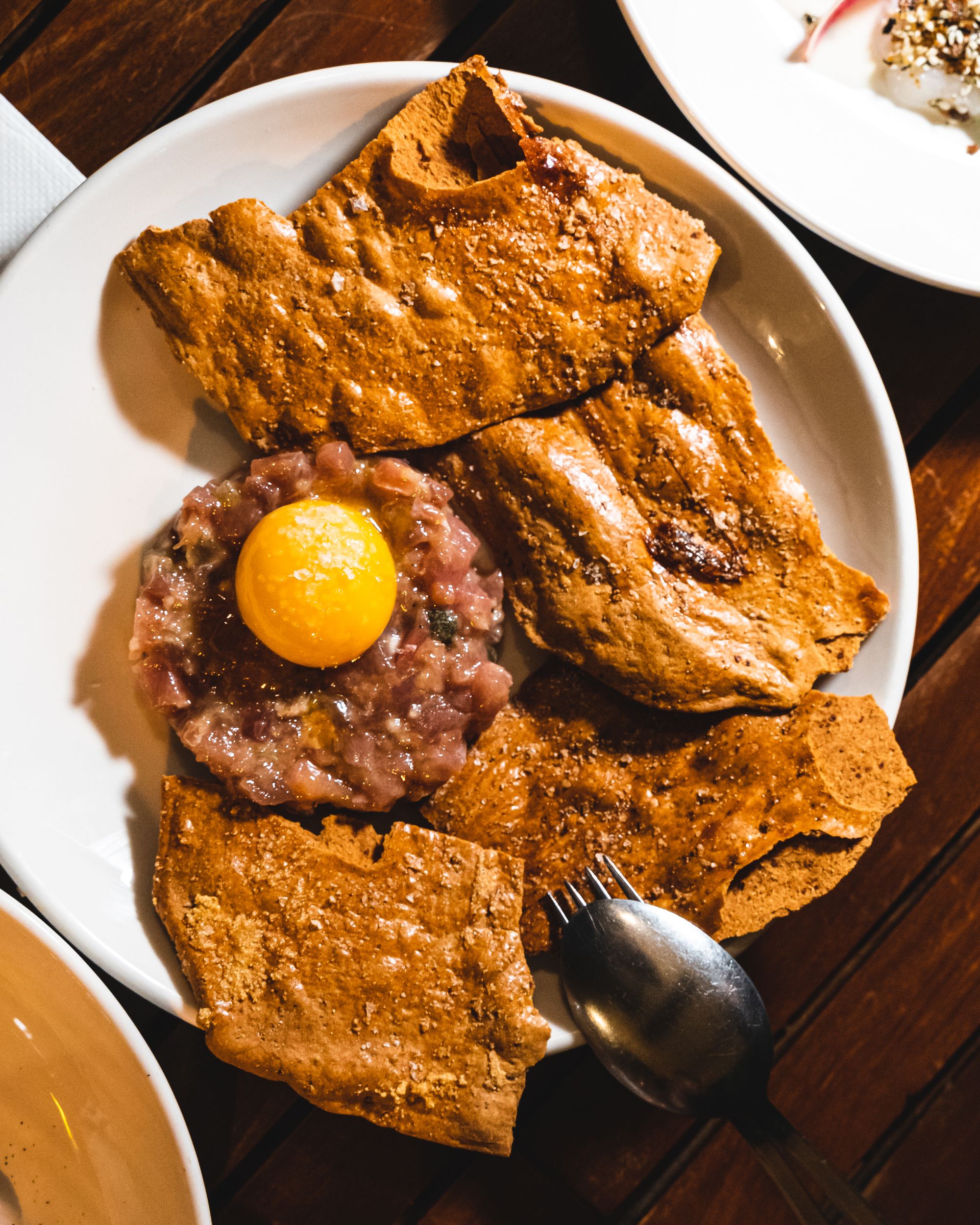 TOp down shot of tuna tartare with an eggyolk with sourdough crisps