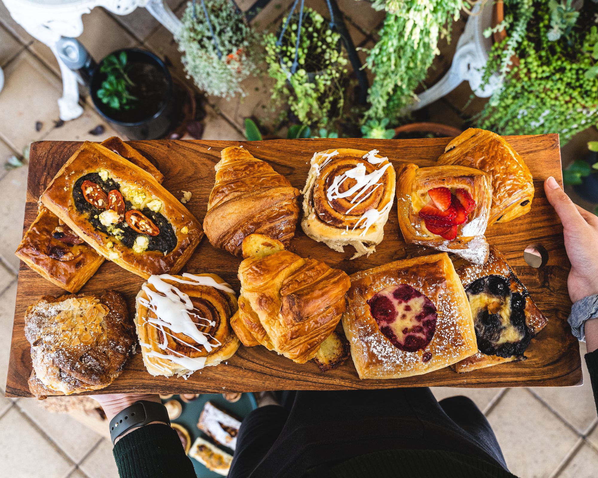 Overhead shot of hands holding a board of assorted pastries