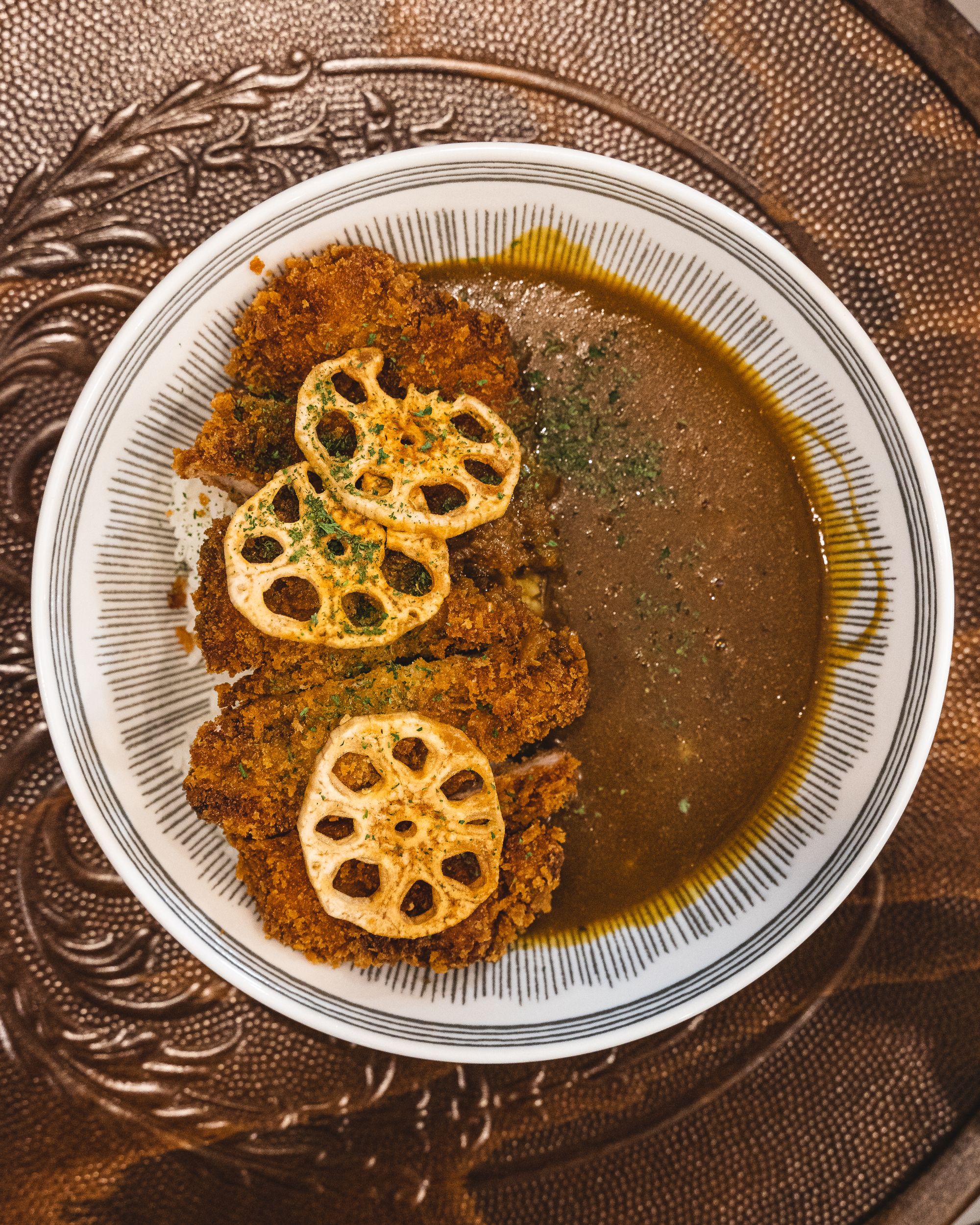 Japanese curry in a plate with chicken katsu and lotus chips.