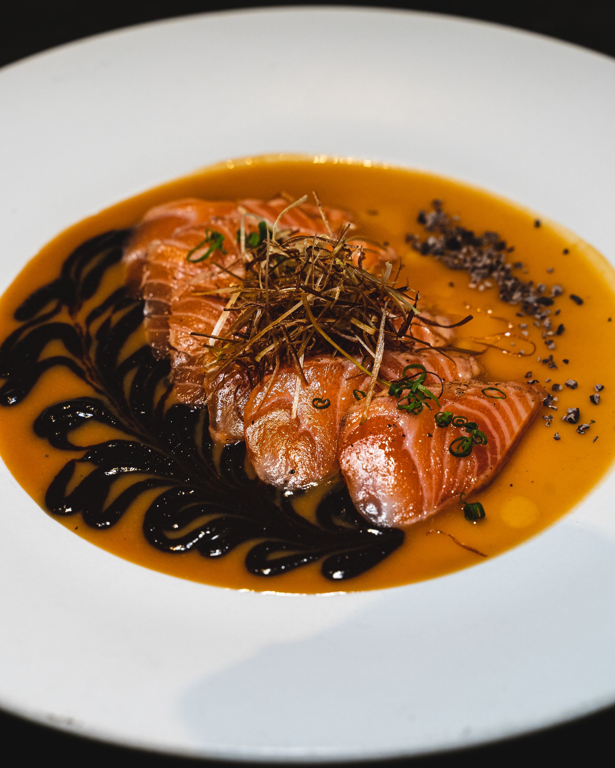 Salmon on a plate with crispy leeks, chocolate and mustard sauce