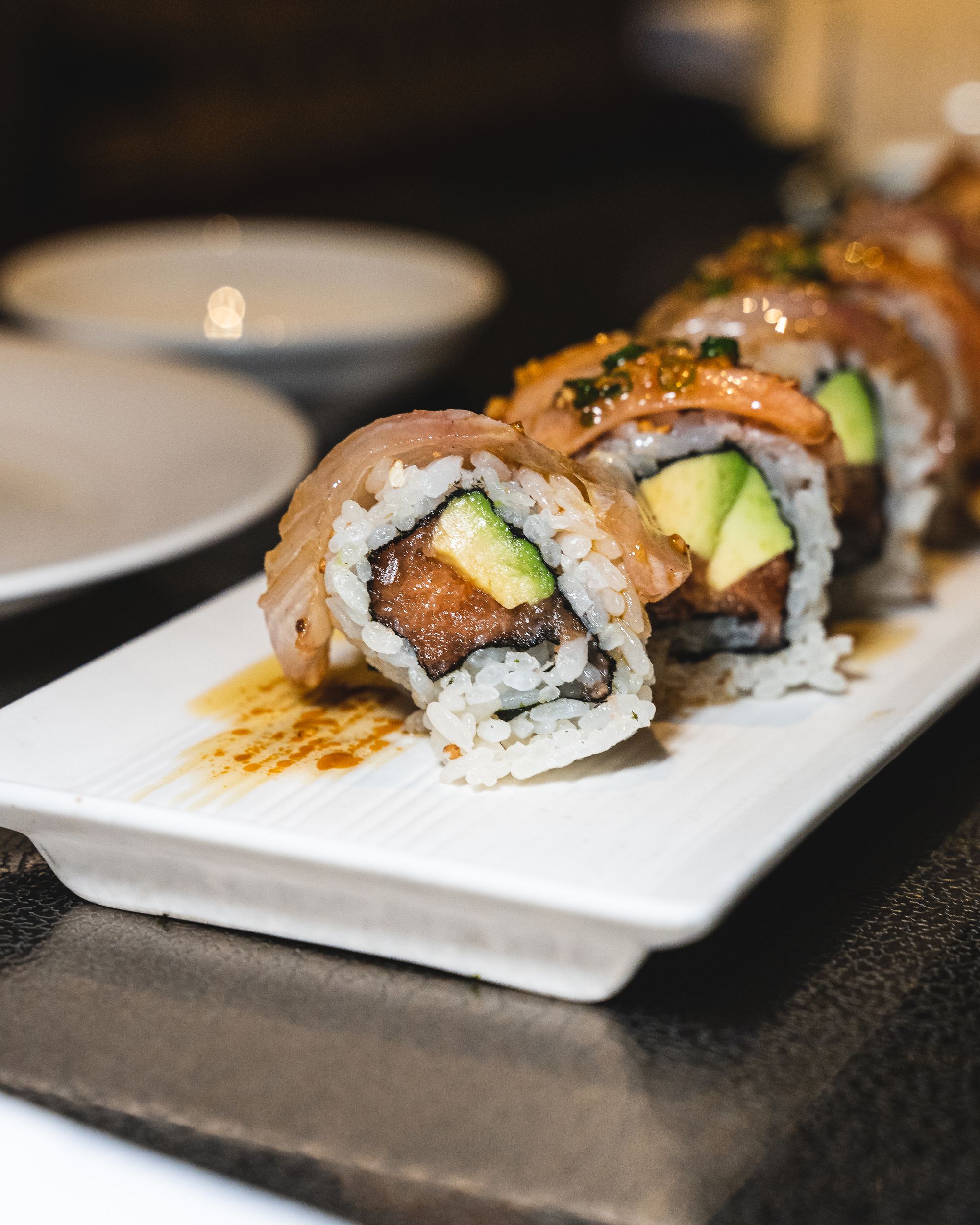 Sushi roll showing avocao and salmon with whitefish on-top