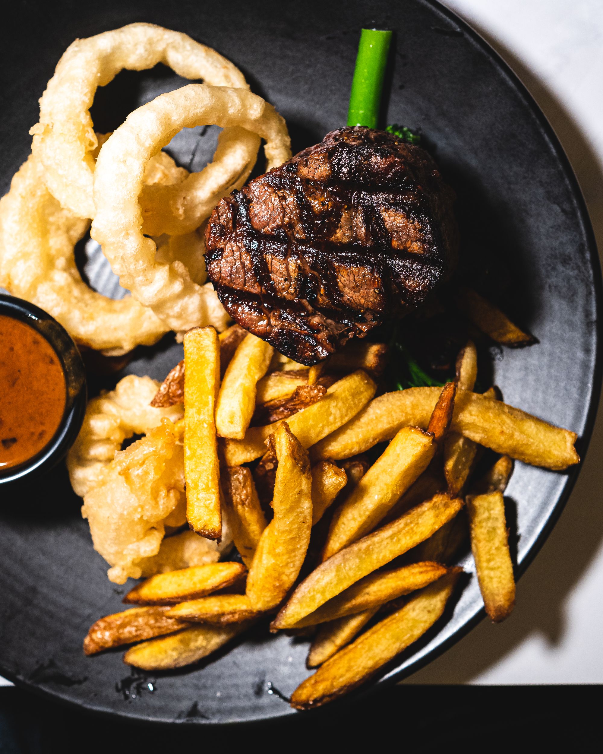 Grilled steak with chips, onion rings and mushroom sauce