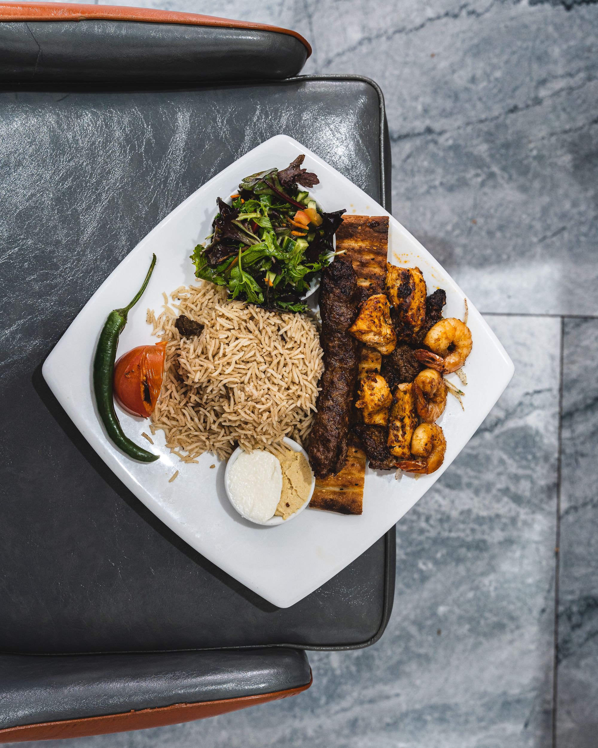 Plate with mixed kebab meat, chilli, hummus and rice