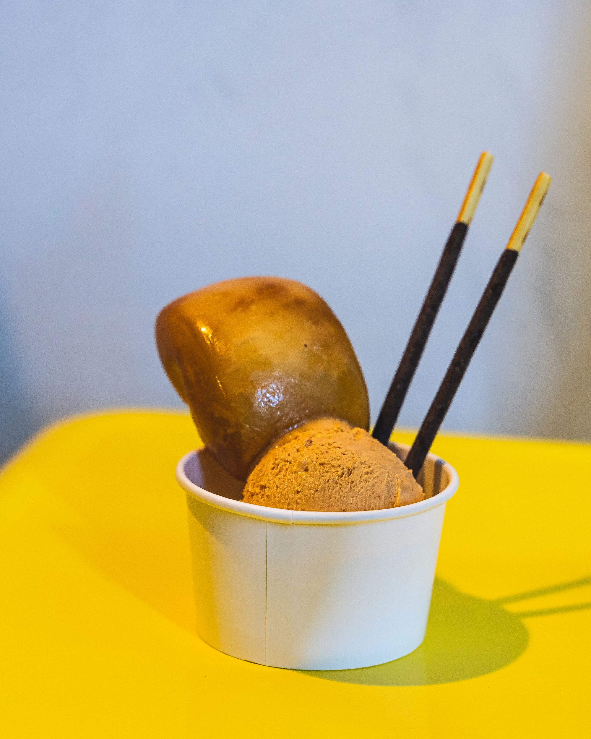 Close up of gelato in a cup with two Pocky sticks and a mantou