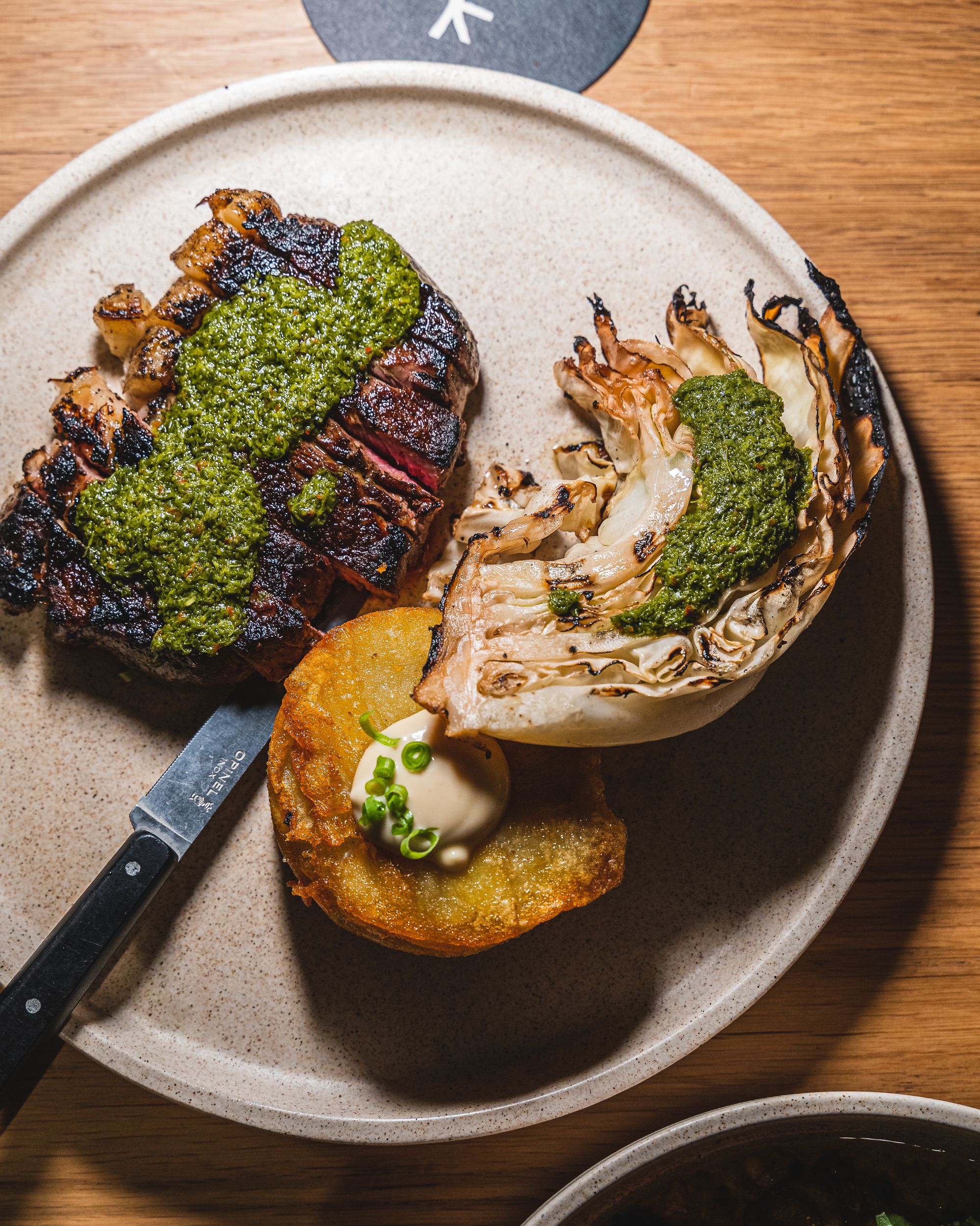 Top down shot of sirloin steak with chimichuri, potato and roasted cabbage