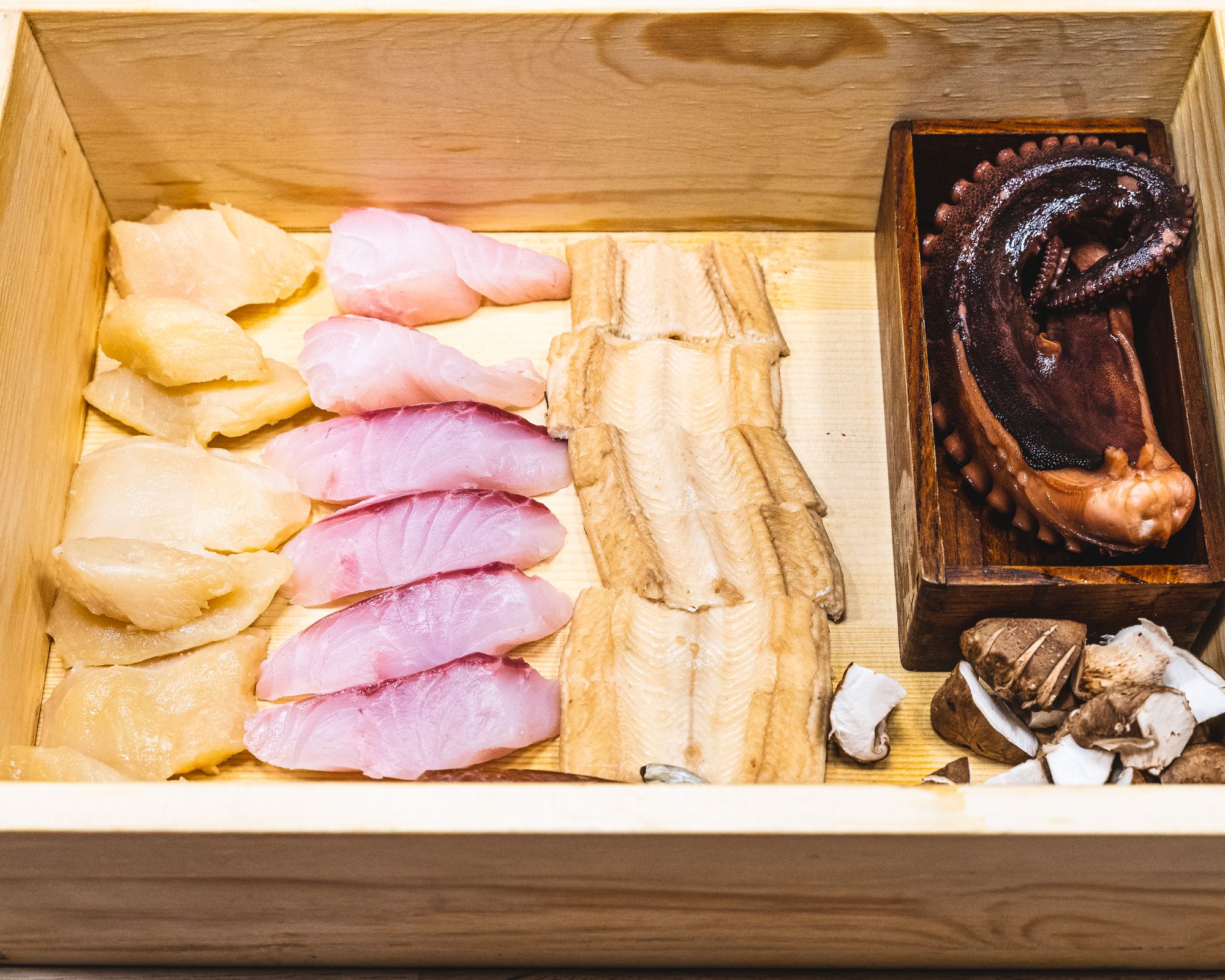 Wooden box with various cuts of fish and octopus inside