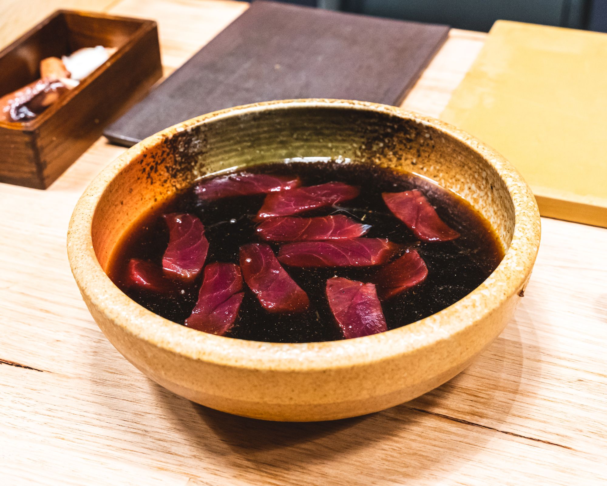 Tuna sashimi marinating in a bowl of soy sauce