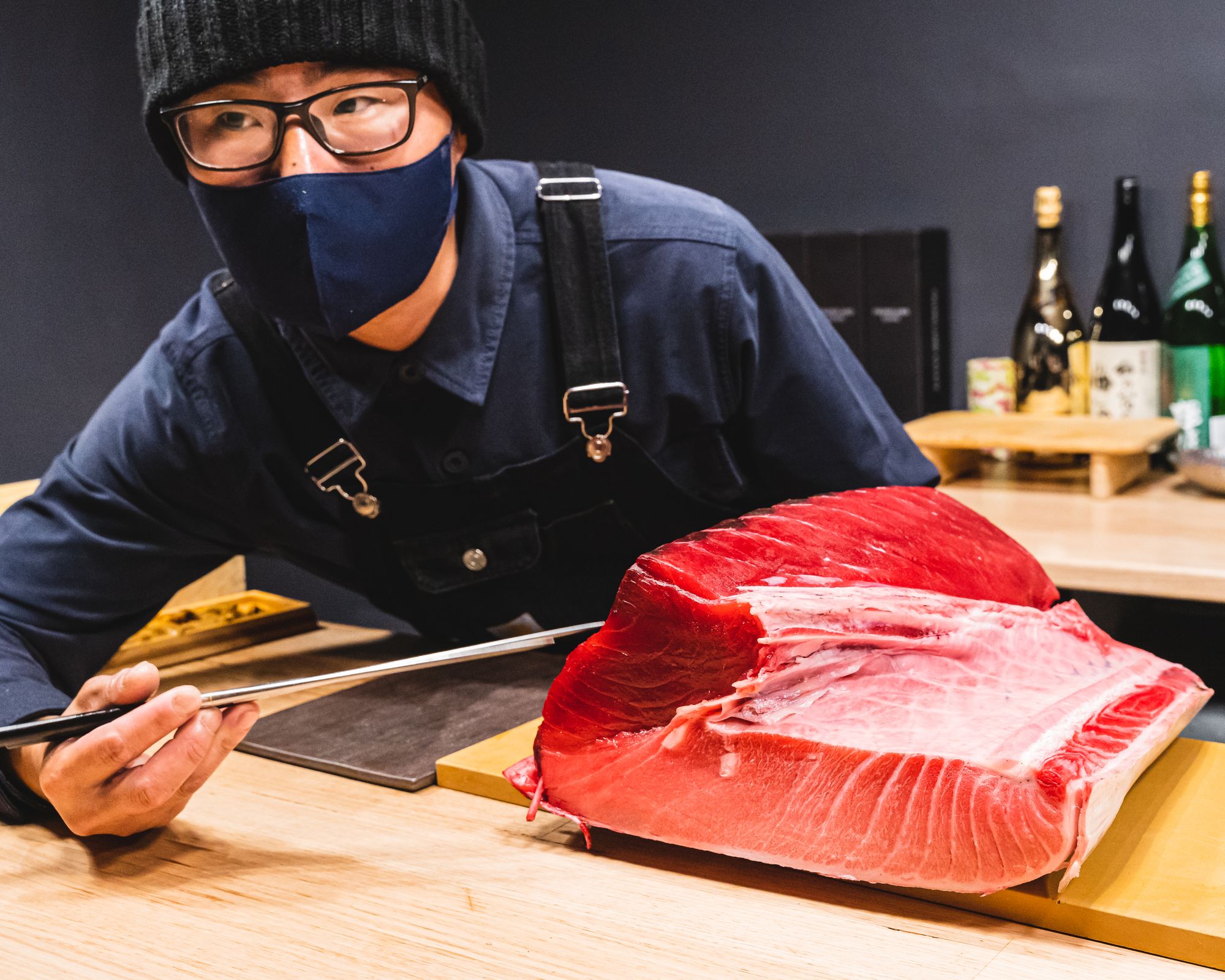 Chef pointing to a chunk of tuna with chopsticks